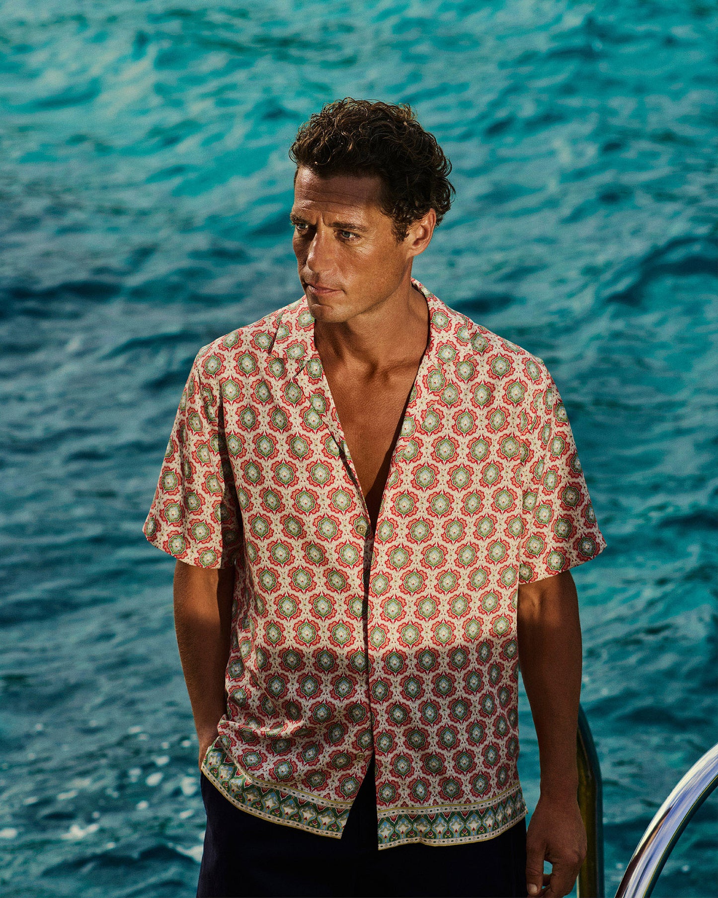 Man wearing a patterned shirt standing by the ocean