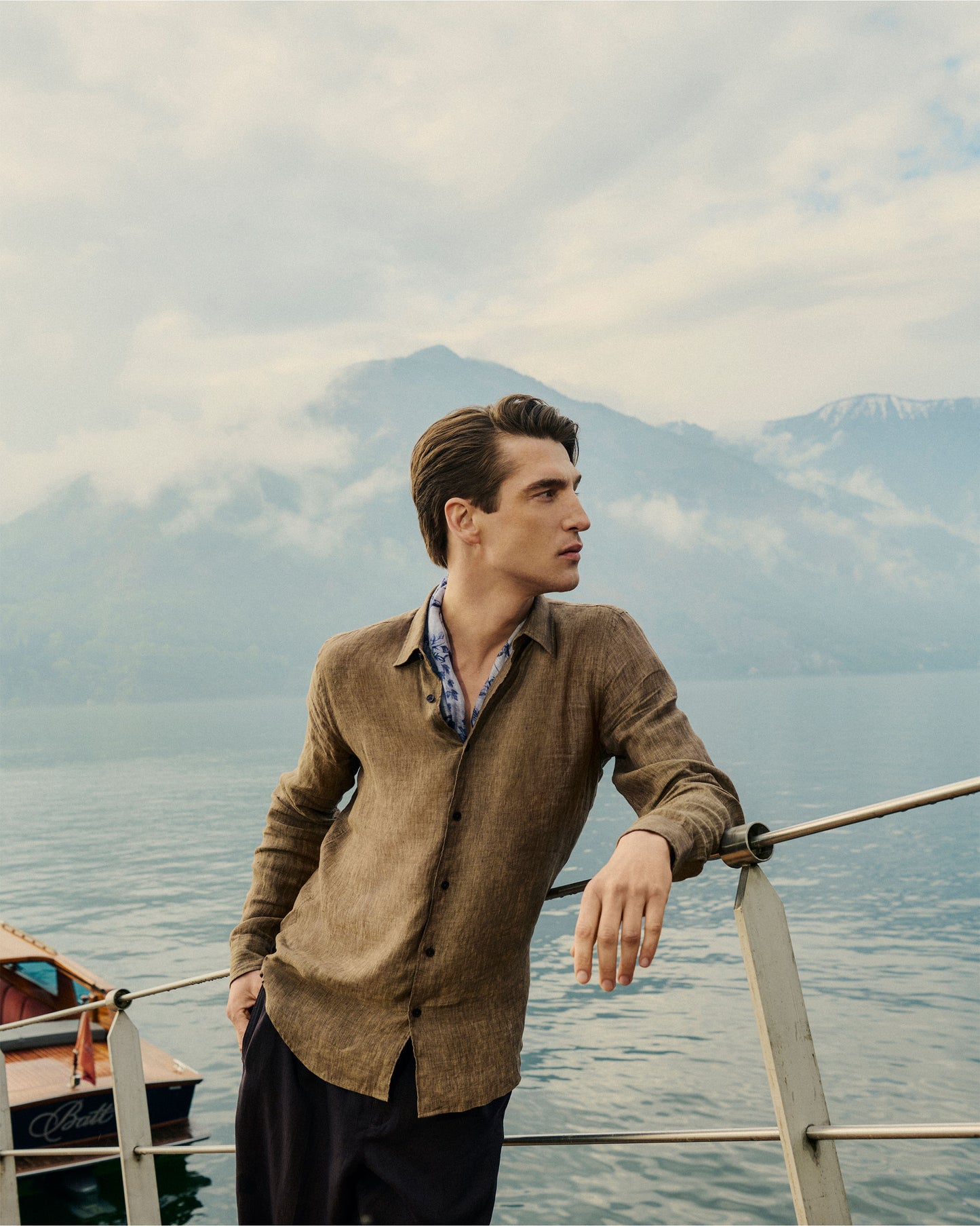 Man standing on a boat with mountains and water in the background