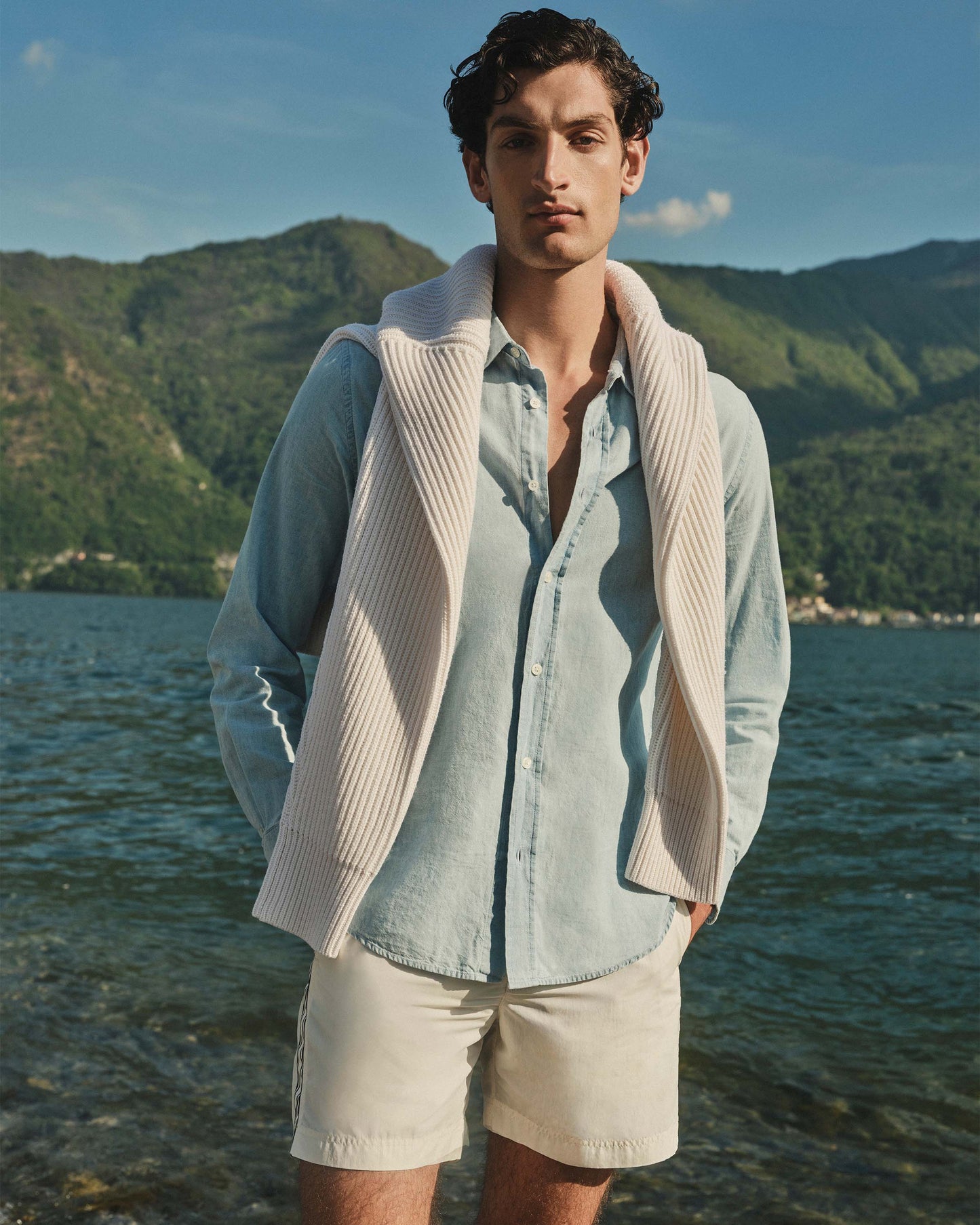 Man standing by a body of water with mountains in the background