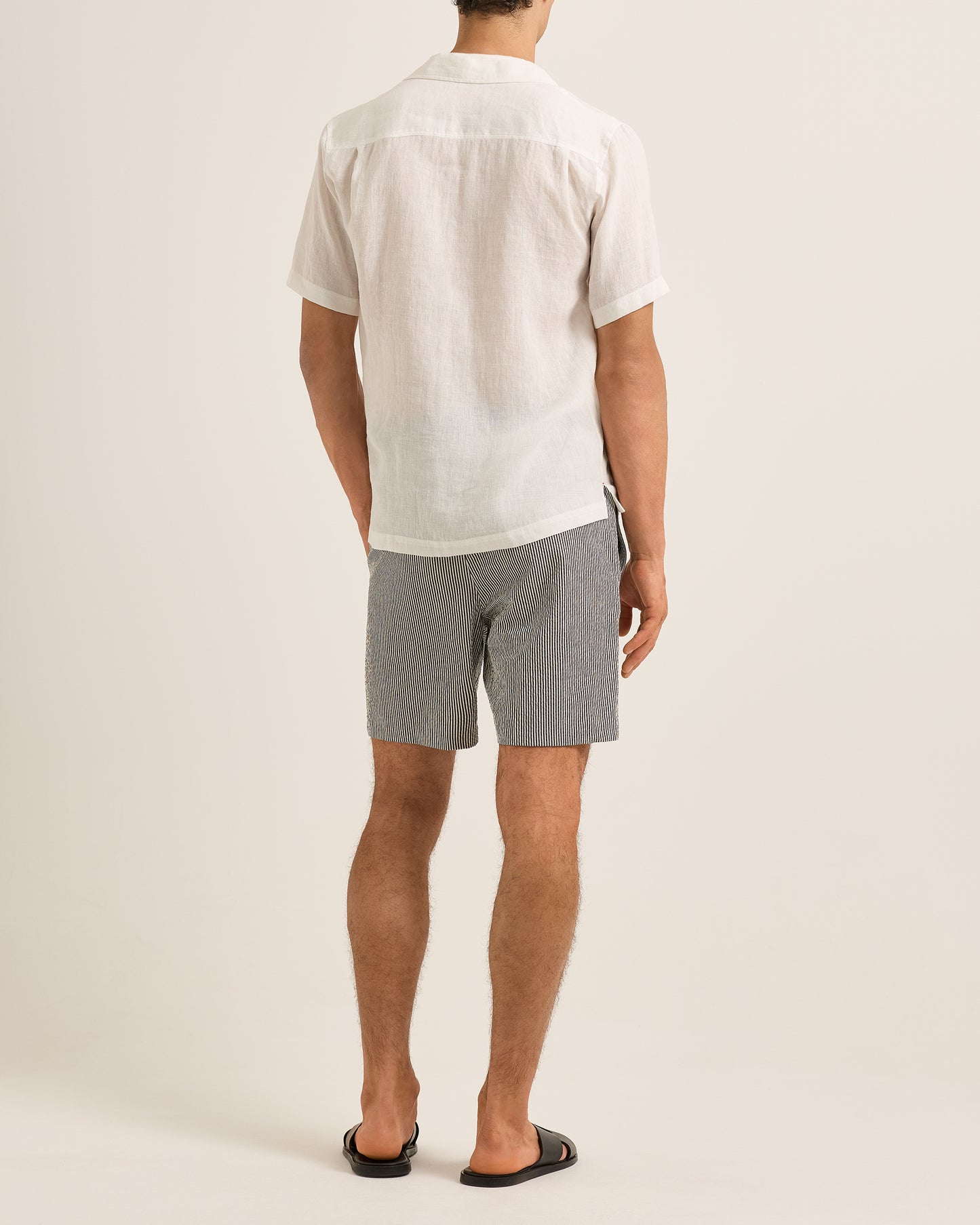 Person wearing a white shirt and gray shorts on a plain background