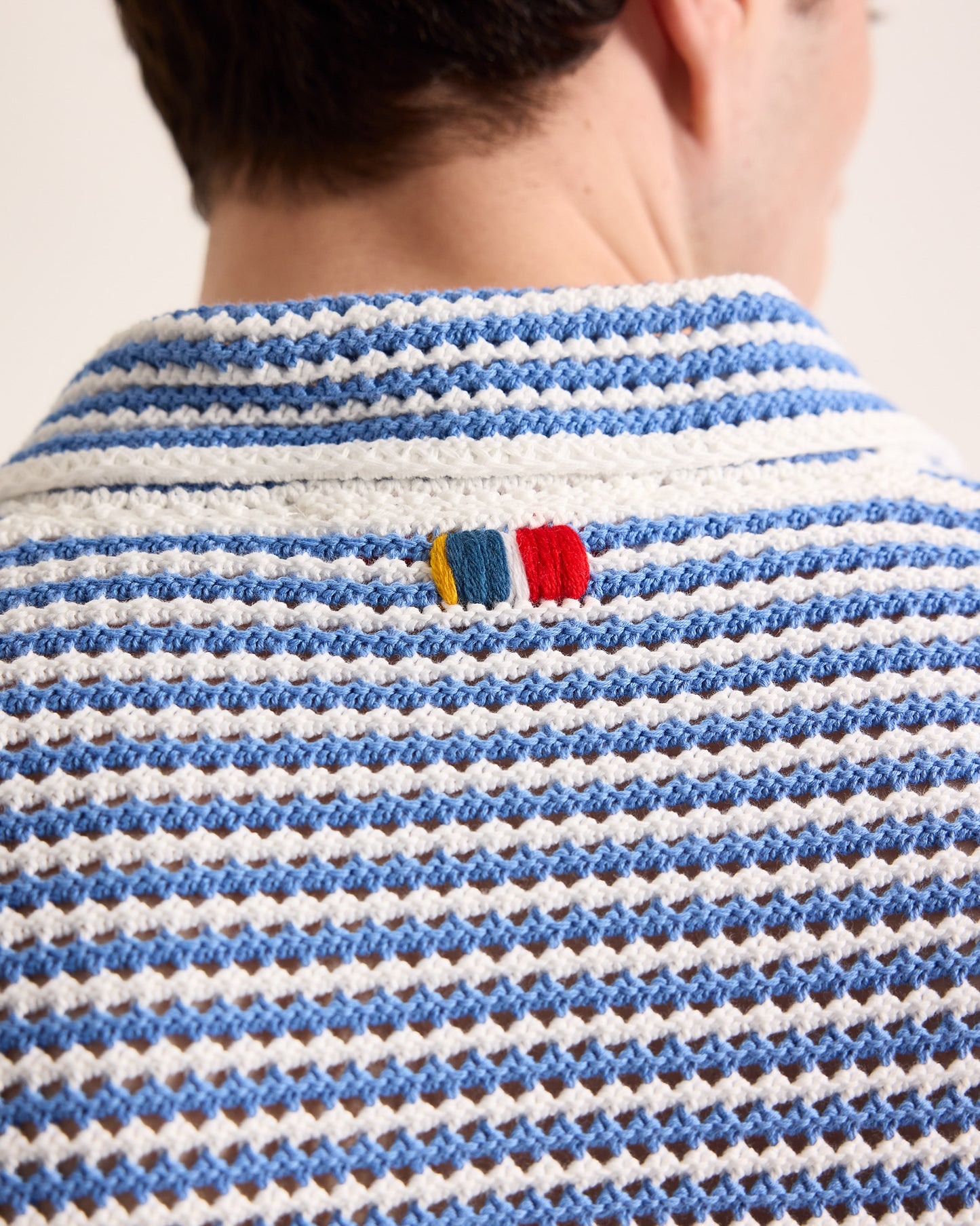 Close-up of a person wearing a blue and white striped shirt with a colorful label.