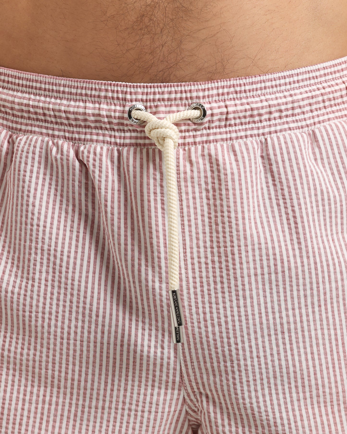 Close-up of red and white striped shorts with a drawstring on a person's waist.