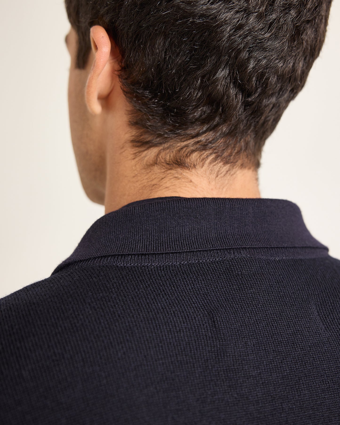 Closeup detail of navy knitted jacket on a plain background
