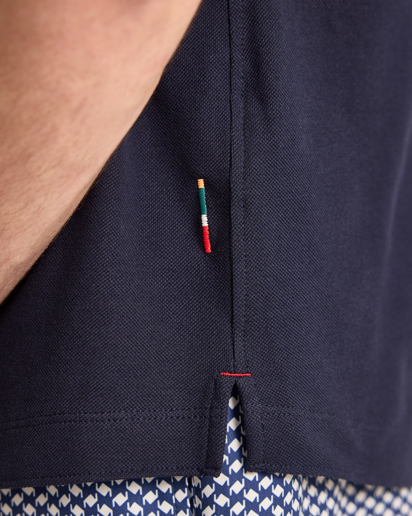 Closeup of navy polo shirt with colourful brand detailing