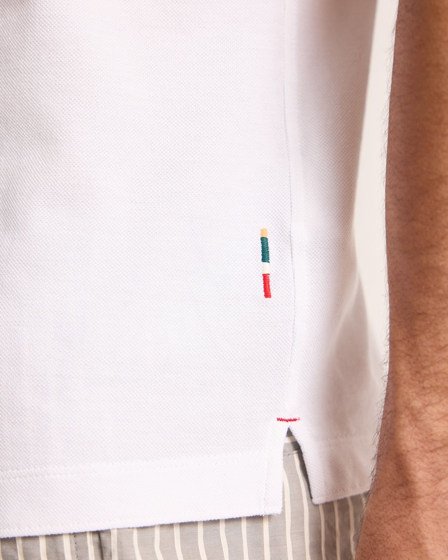 Close-up of a white shirt with colorful embroidery on a person wearing it.