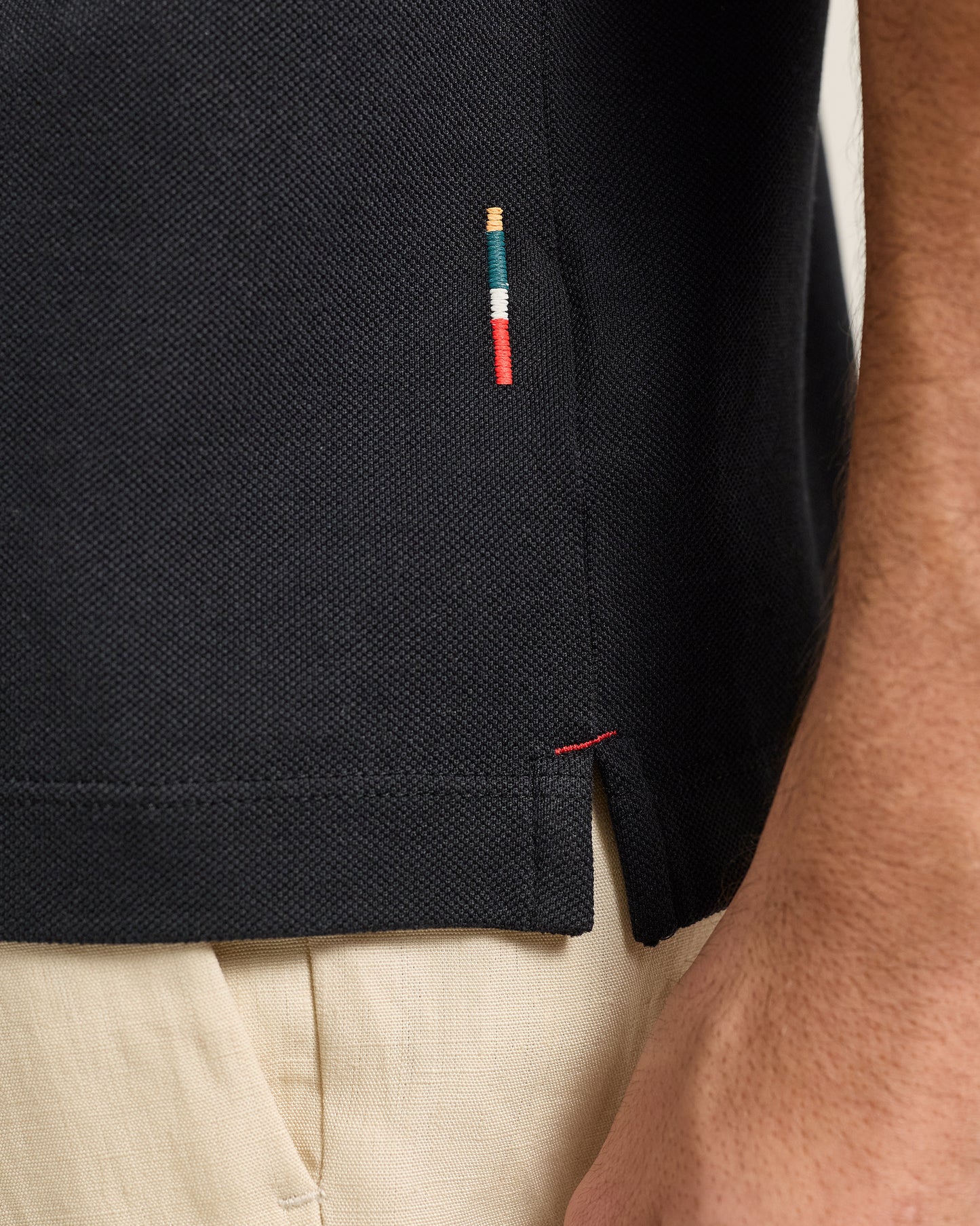 Close-up of a black polo shirt with a small embroidered design on the chest pocket.