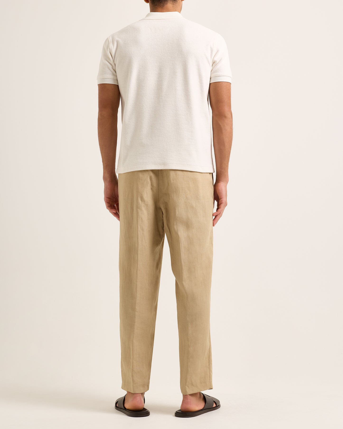 Model wearing light cream polo with beige trousers on a white background