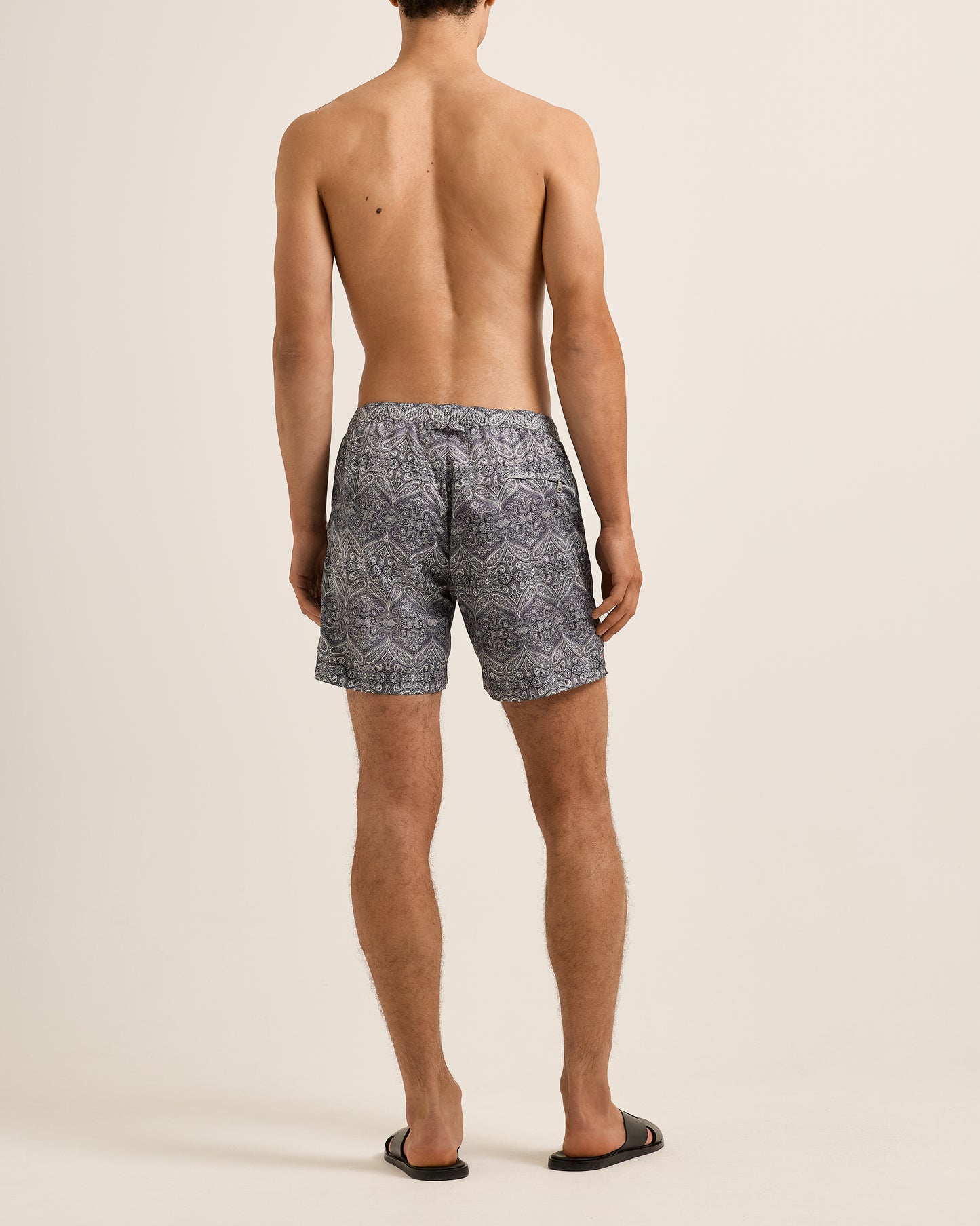 Person wearing patterned swim shorts on a beige background