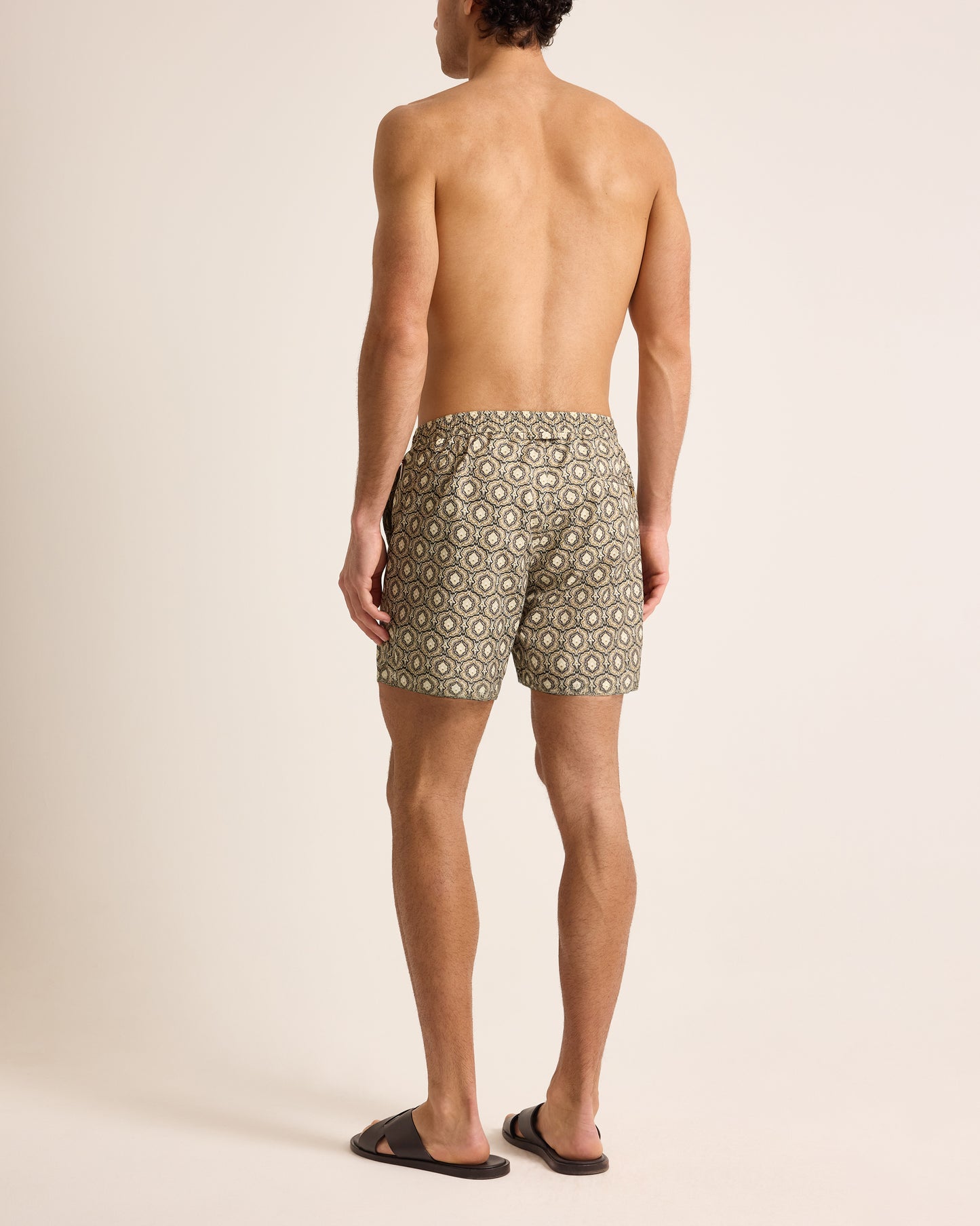 Man wearing beige patterned swim shorts on a beige background