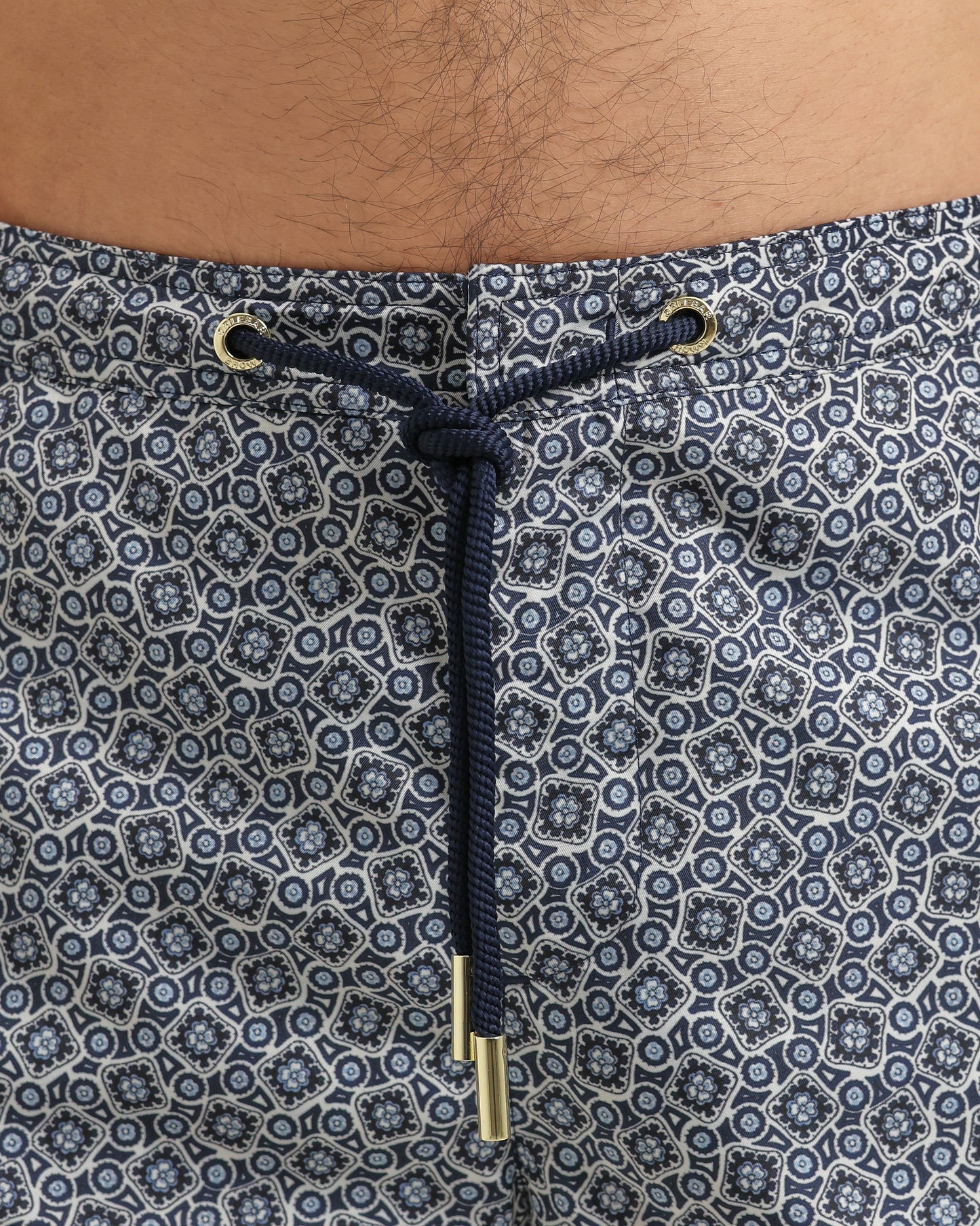 Close-up of patterned shorts with a drawstring and metal buckle.