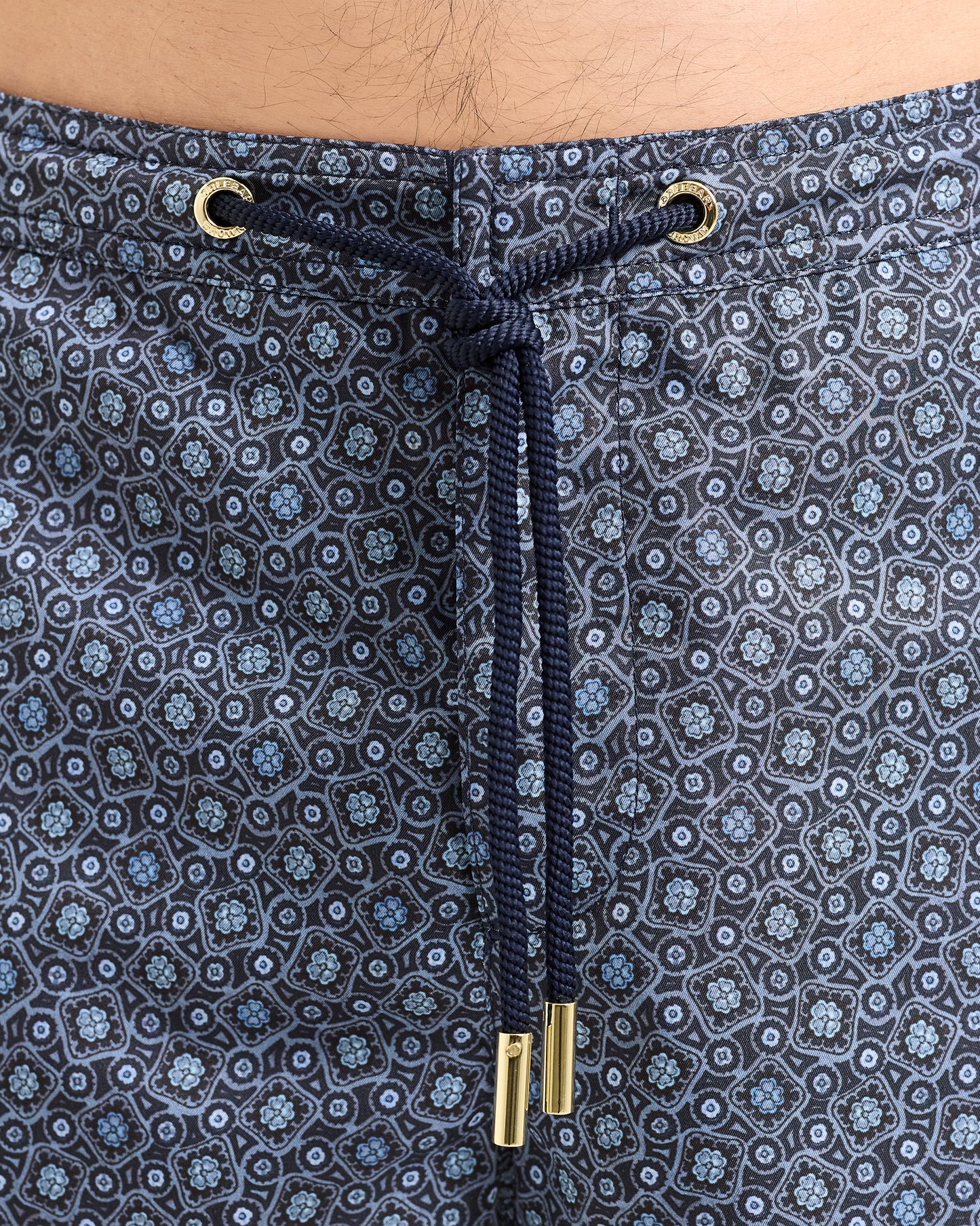 Close-up of navy patterned shorts with drawstring and metal grommets.