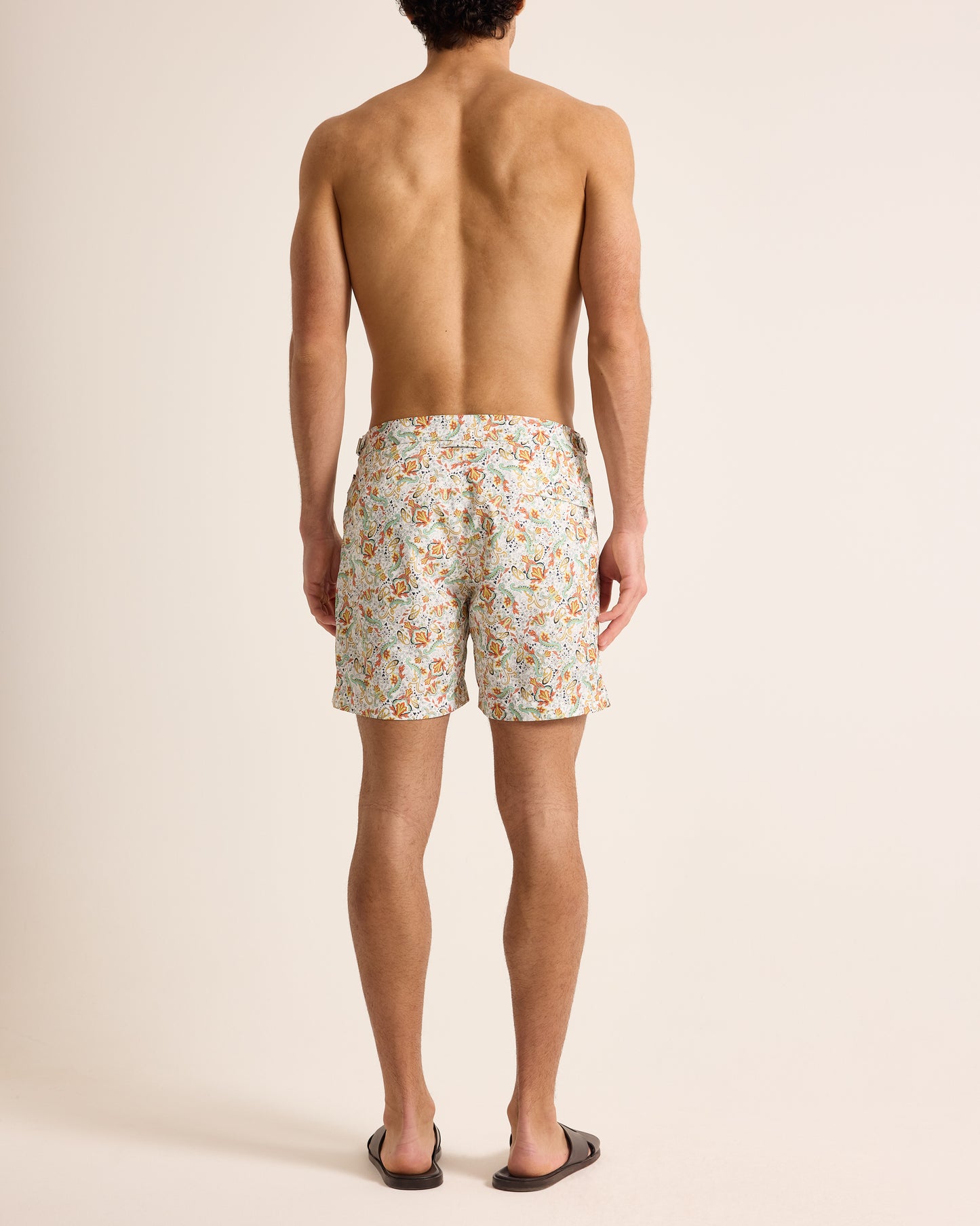Man wearing floral swim shorts on a plain background