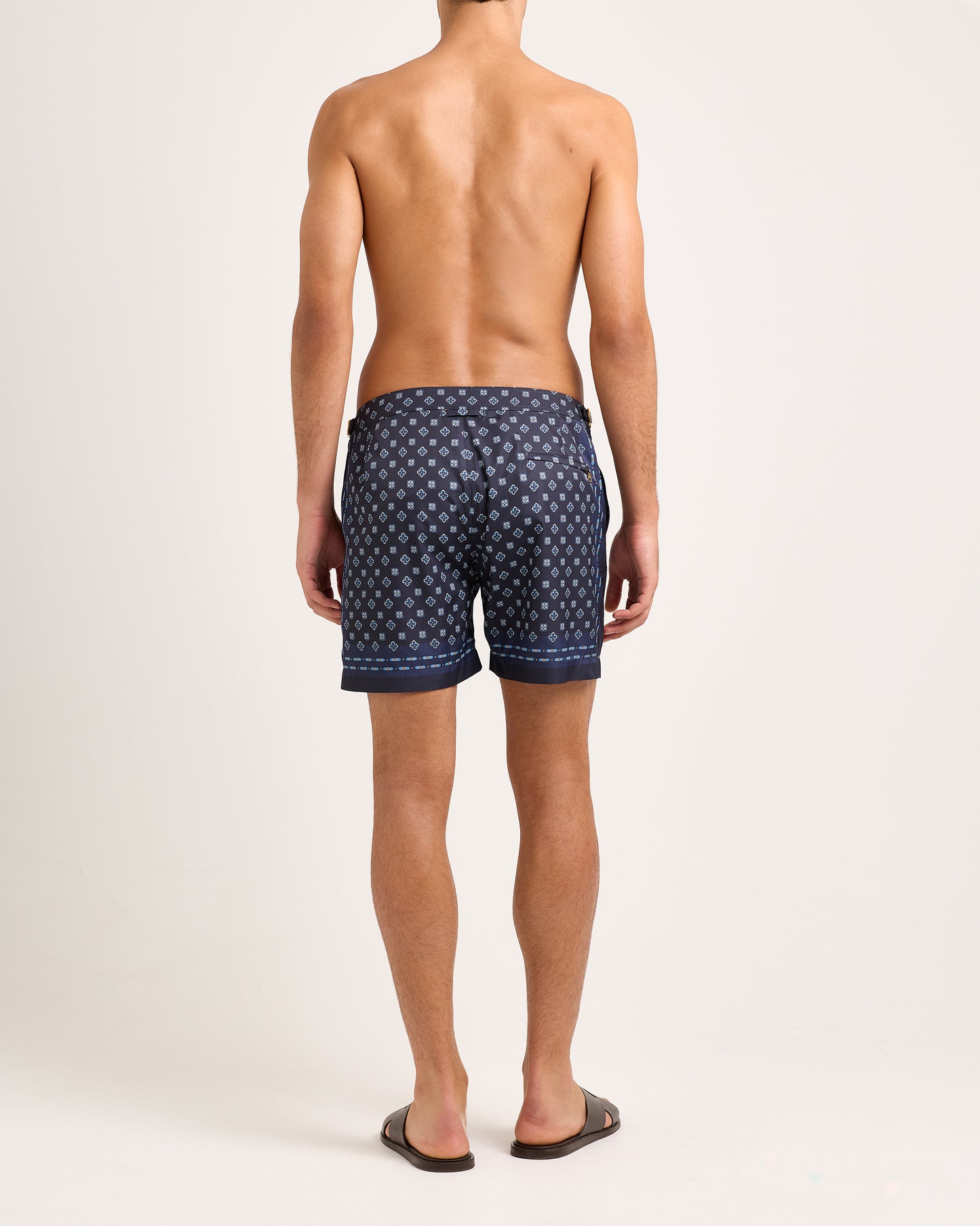 Man wearing navy swim short with geometric pattern on light background