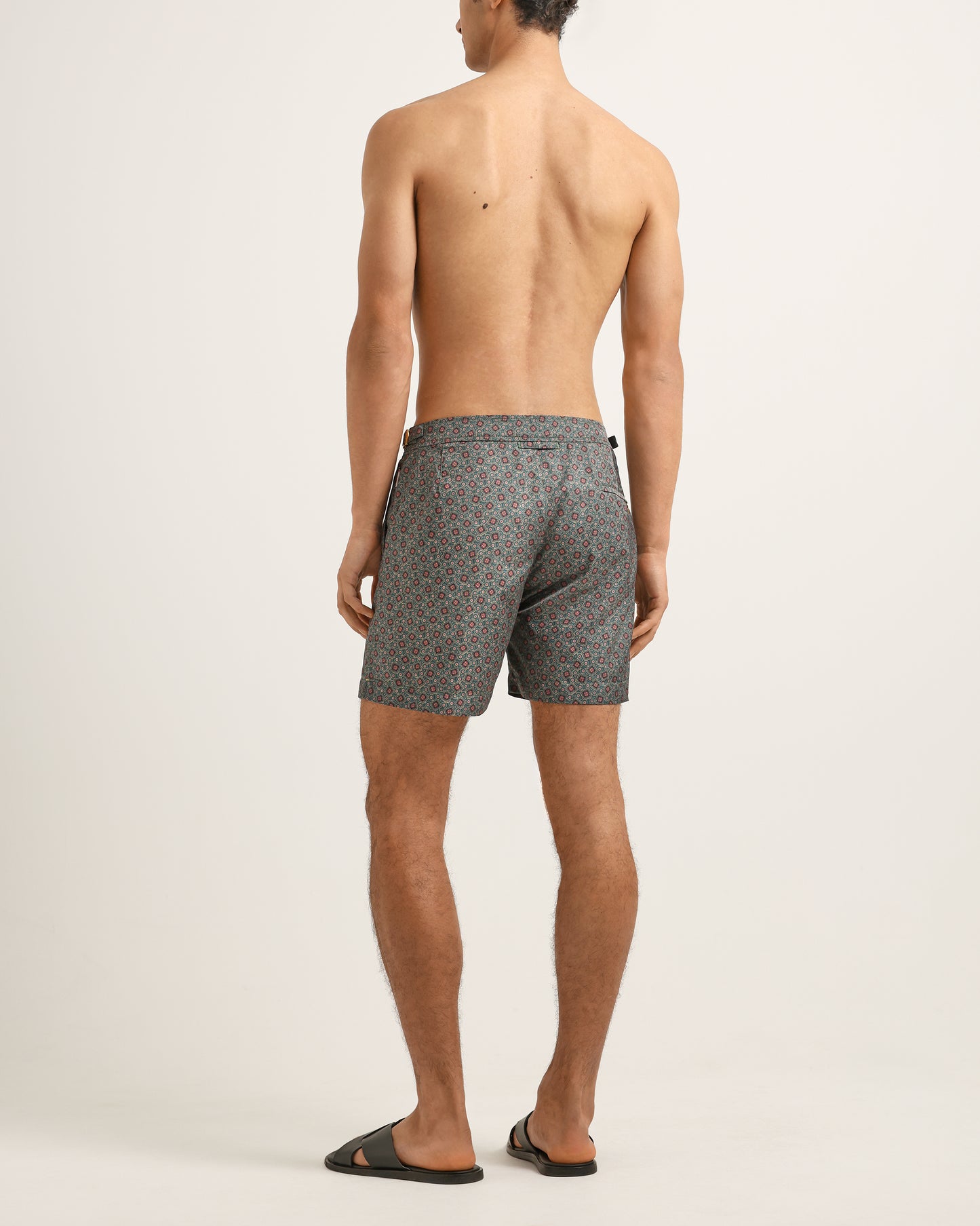 Man wearing gray patterned swim shorts on a plain background
