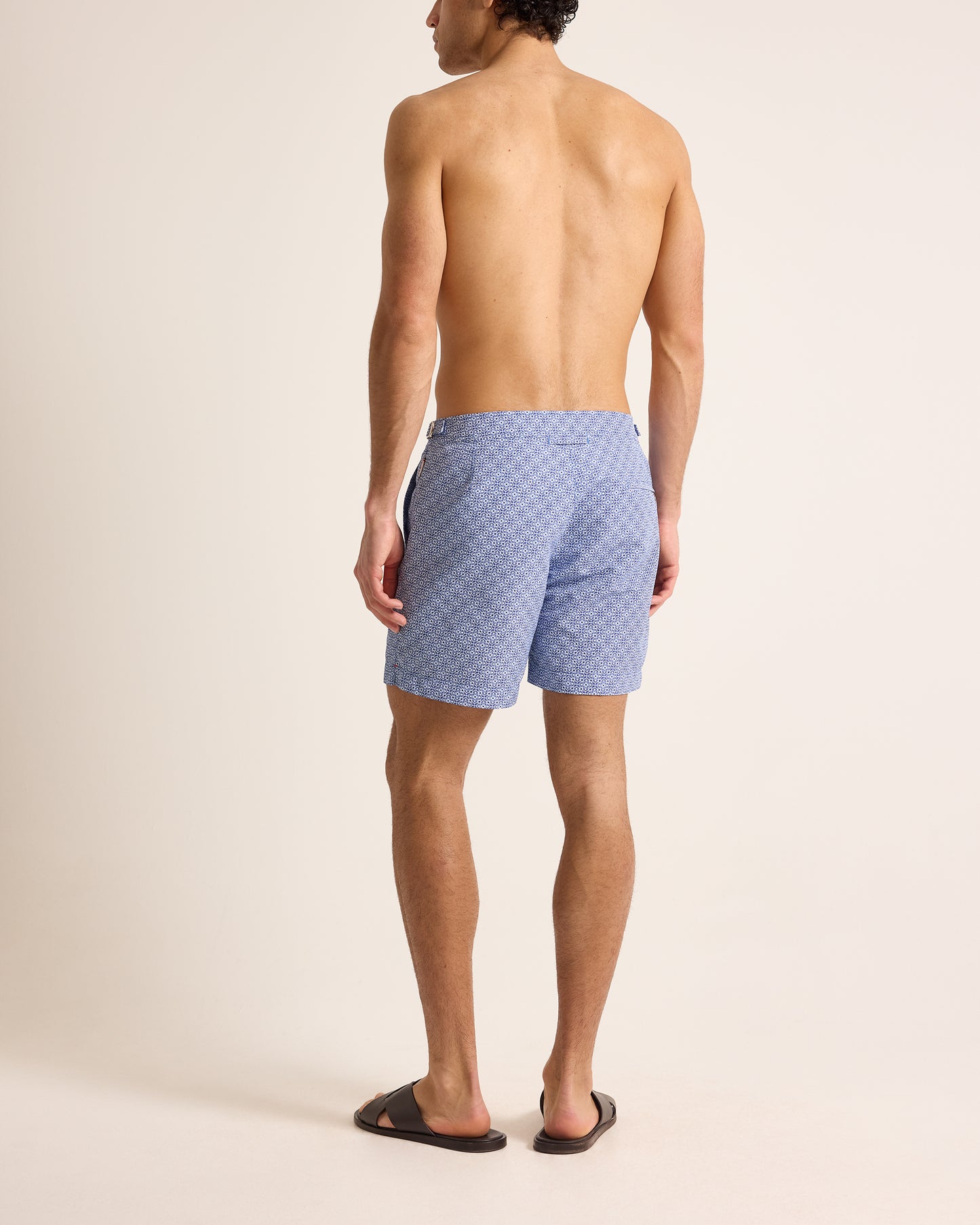 Man wearing blue patterned swim shorts on a beige background