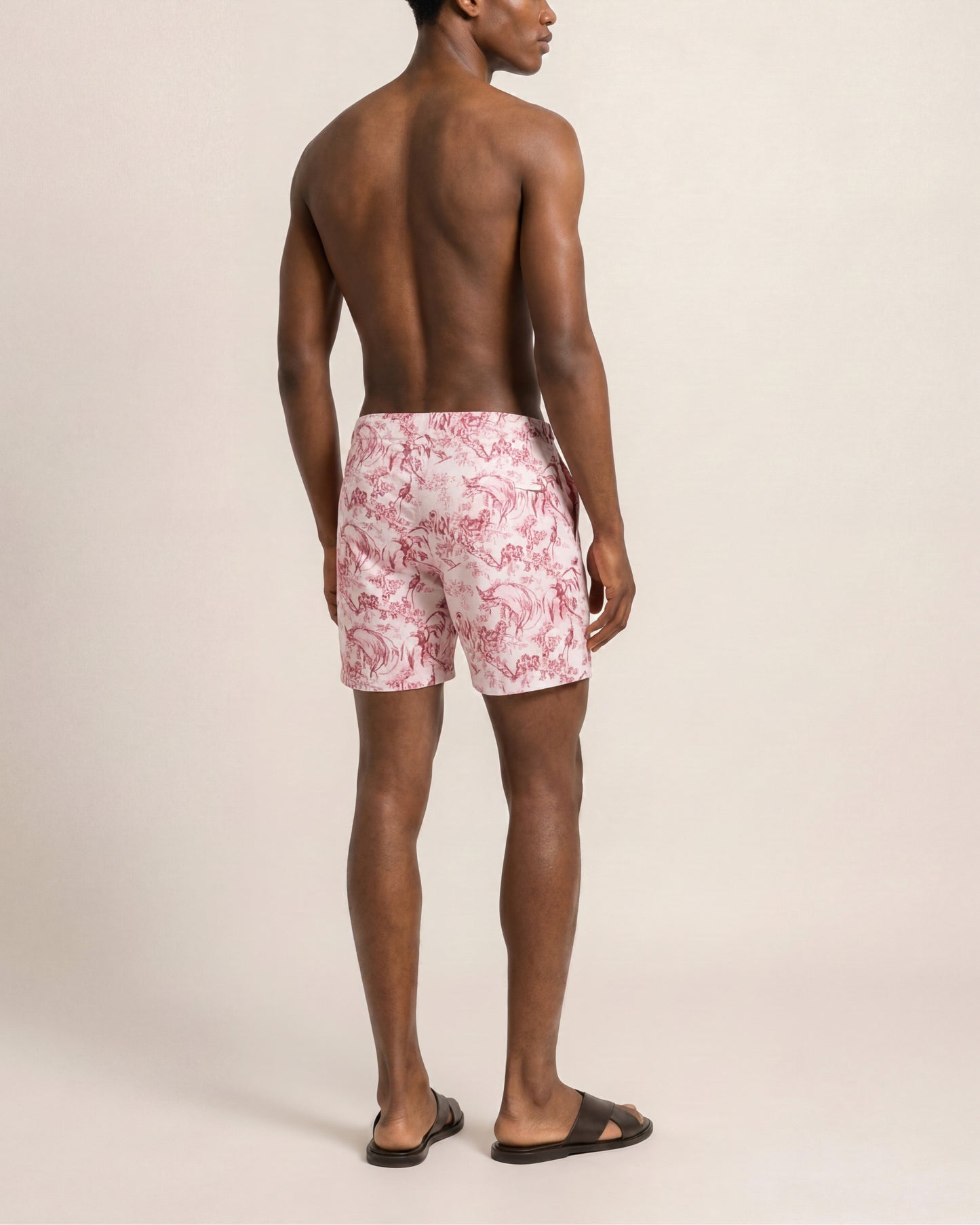 Man wearing pink floral swim shorts on a beige background