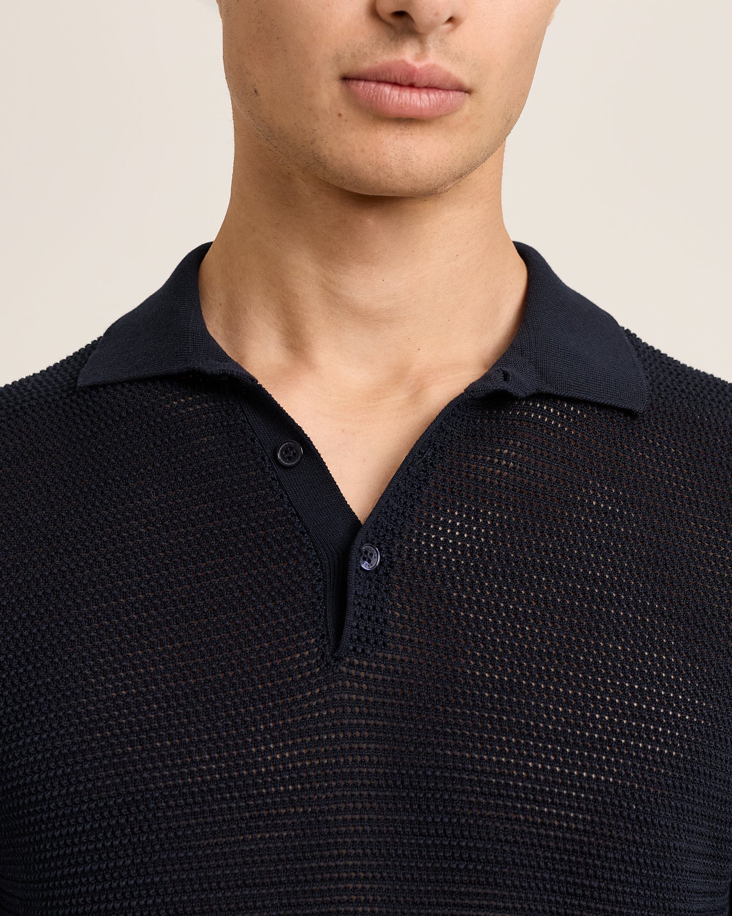 Navy textured polo shirt worn by a person on a beige background