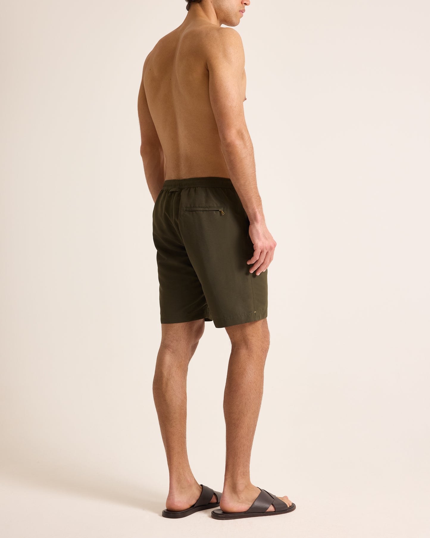 Man wearing olive green shorts on a beige background