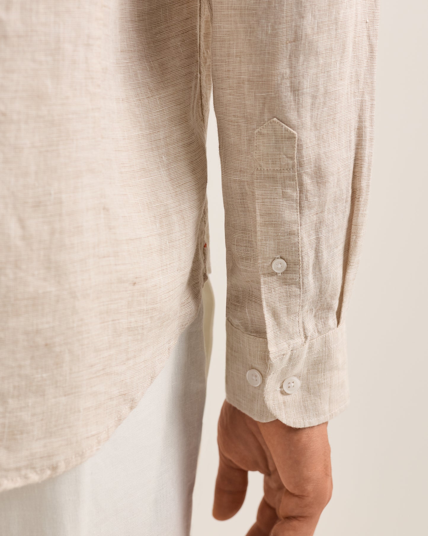 Close-up of a beige linen shirt with buttons on a neutral background