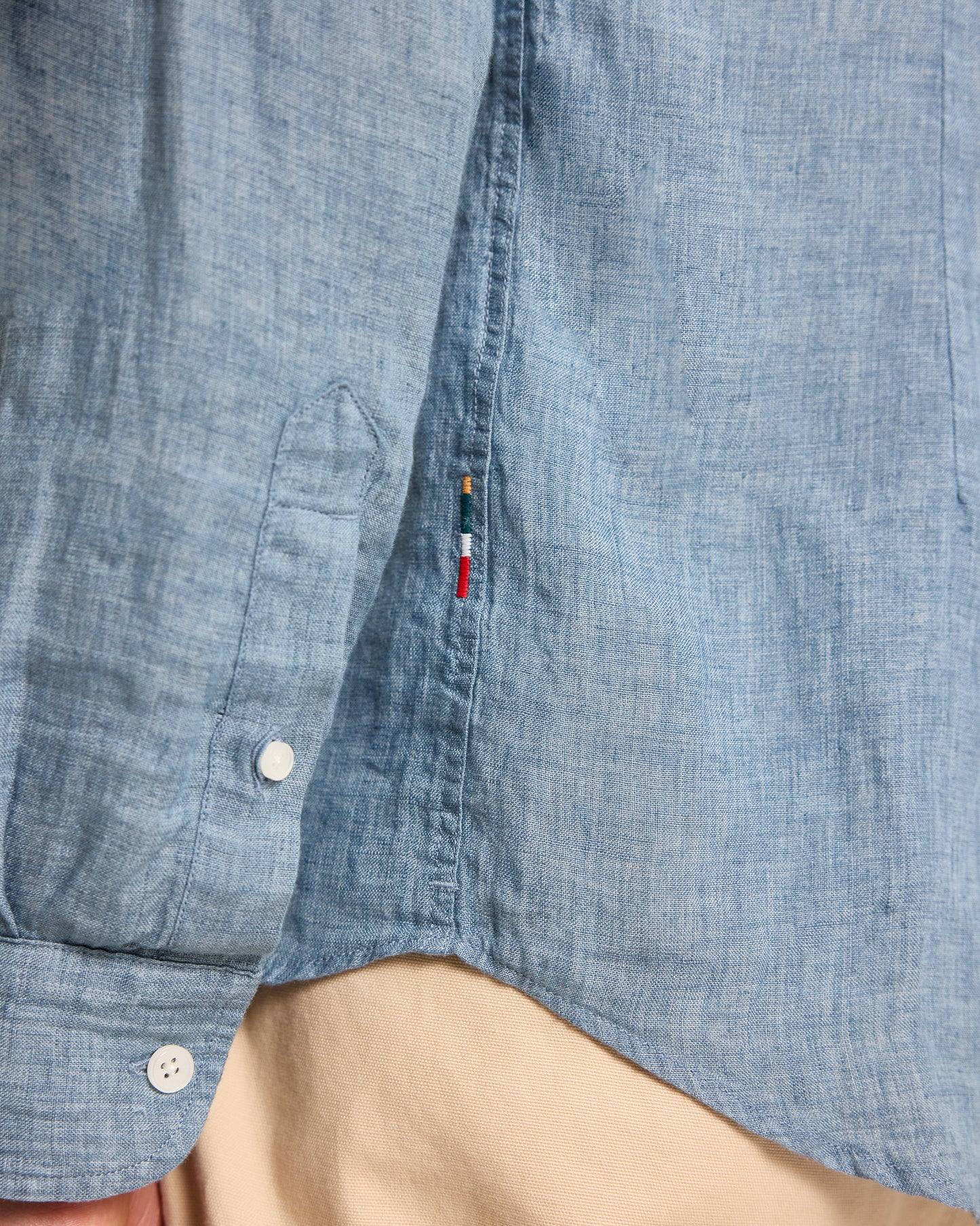 Close-up of a blue denim shirt with a brand logo on a beige background