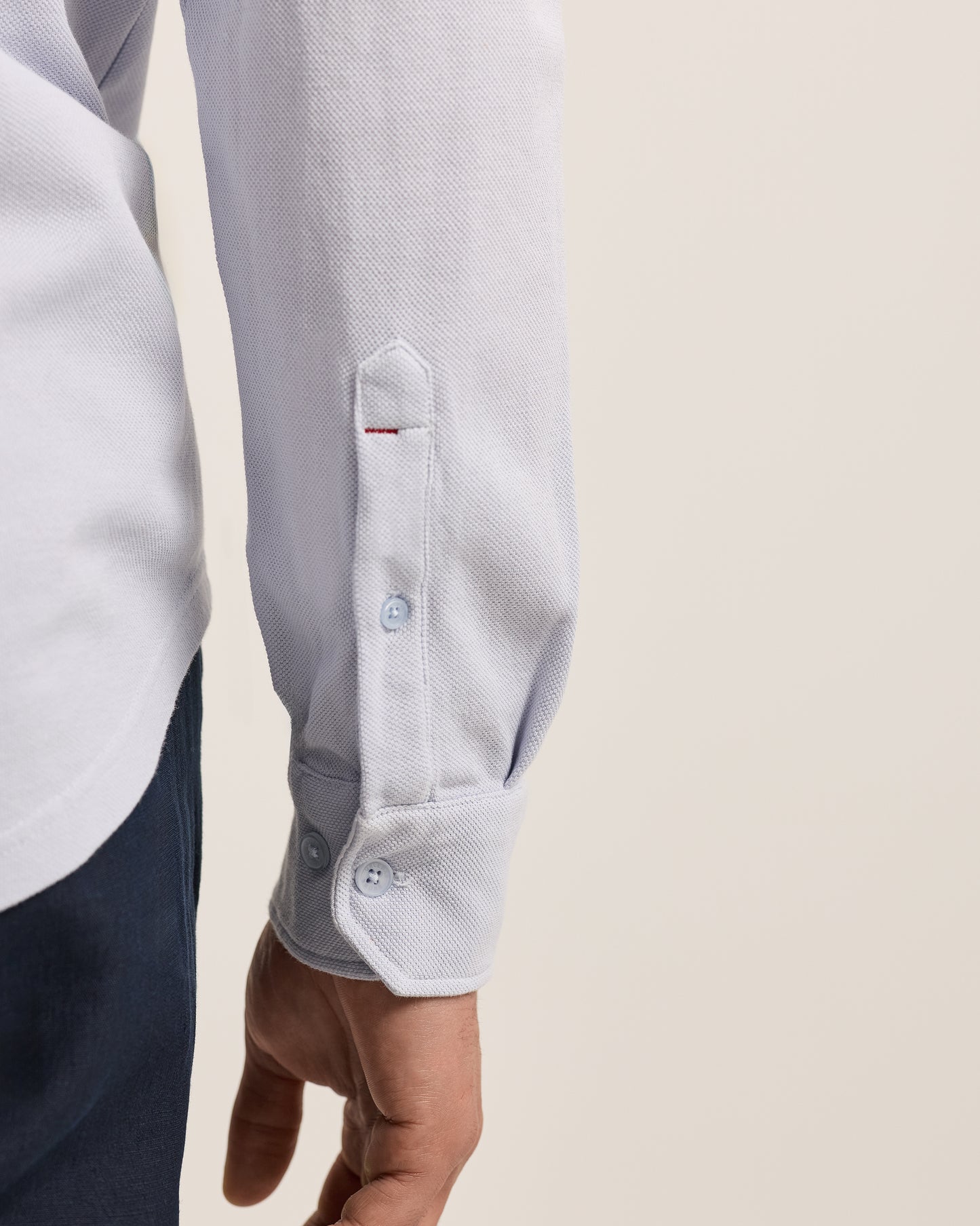 Close-up of a light gray shirt with a button on a beige background
