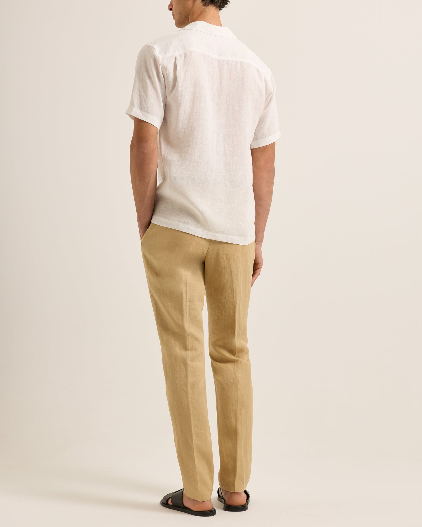 Person wearing a white shirt and beige pants on a plain background