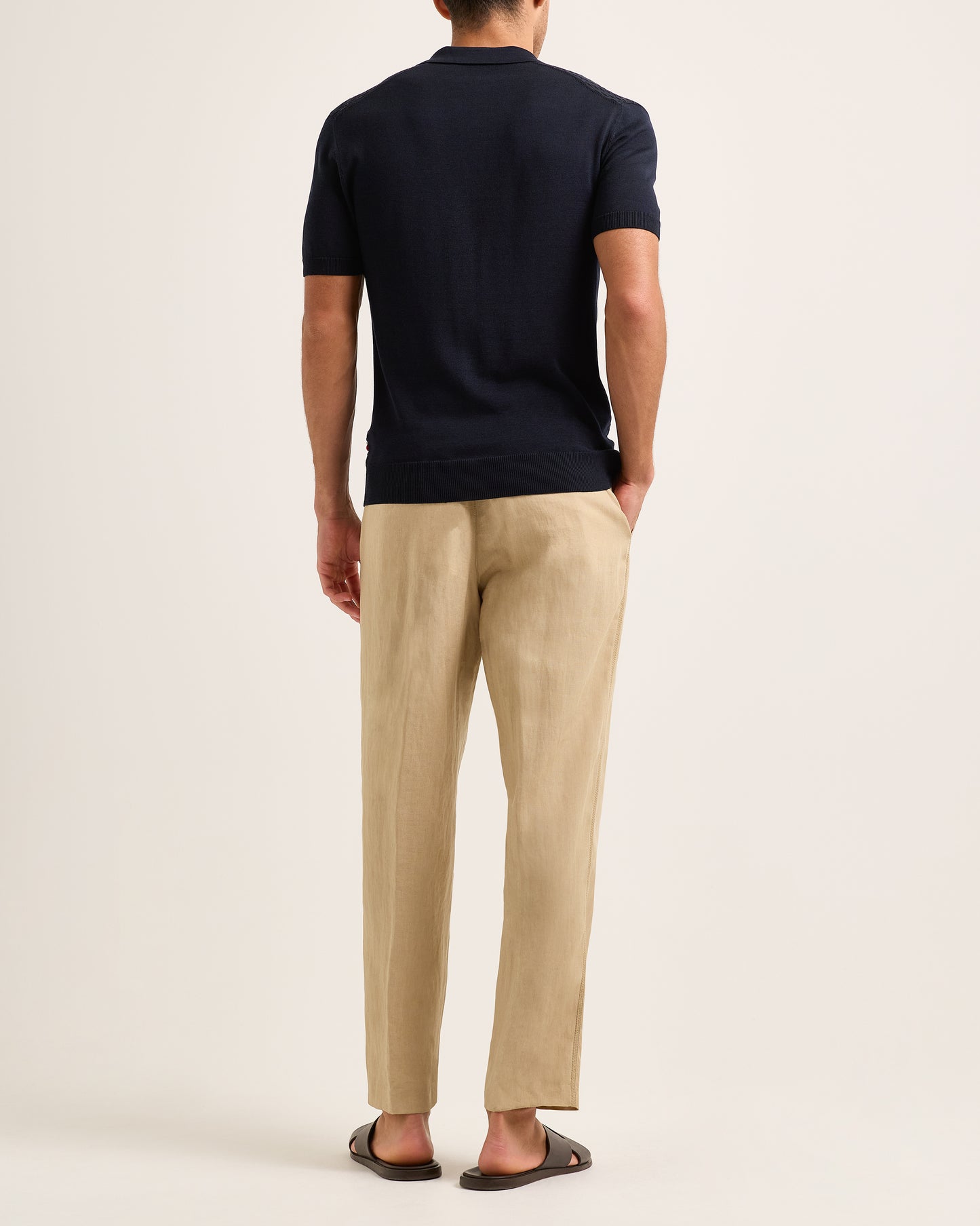 Model wearing navy textured polo shirt with beige trousers on a plain background