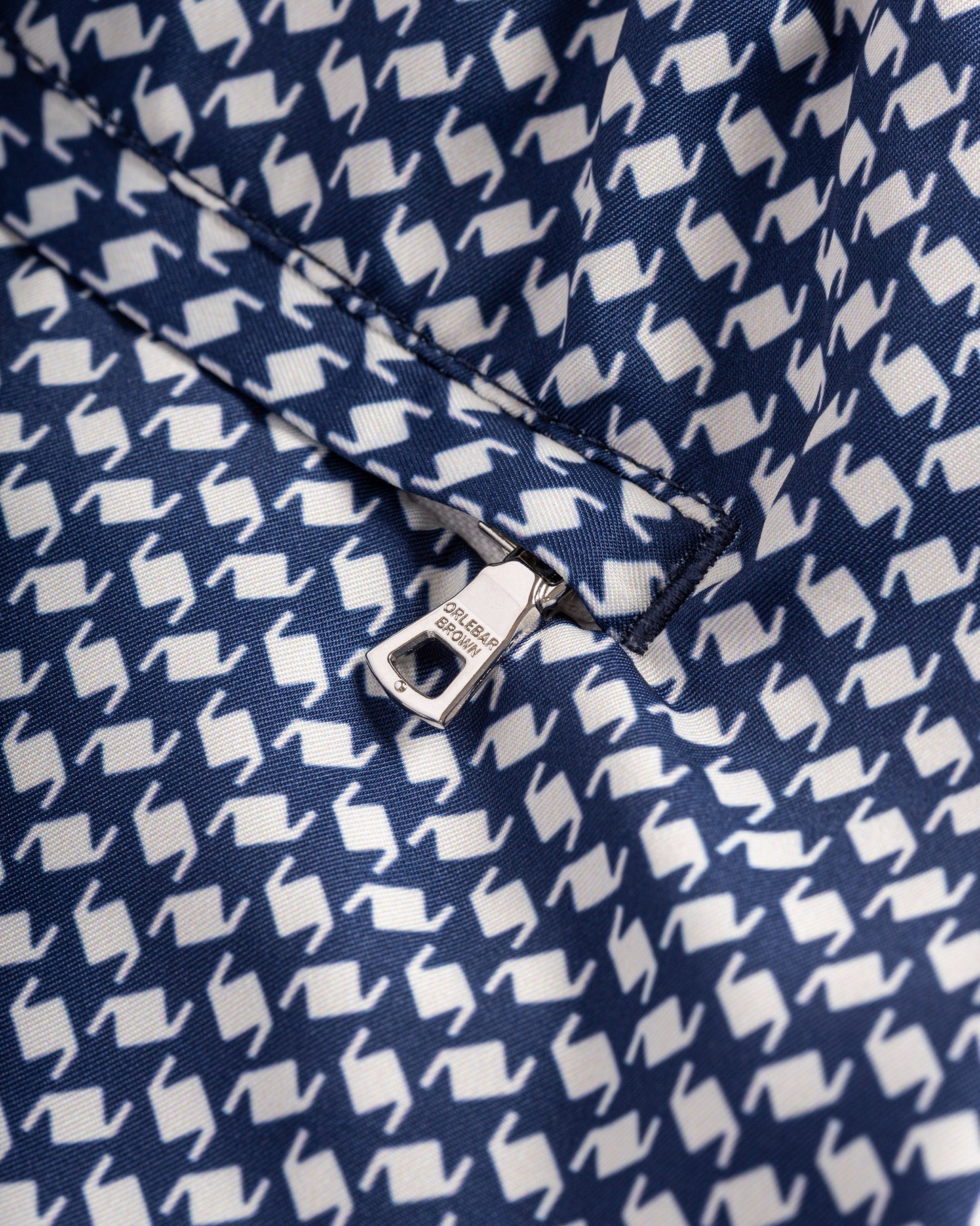 Close-up of a navy blue fabric with white geometric pattern and Colmar brand tag.