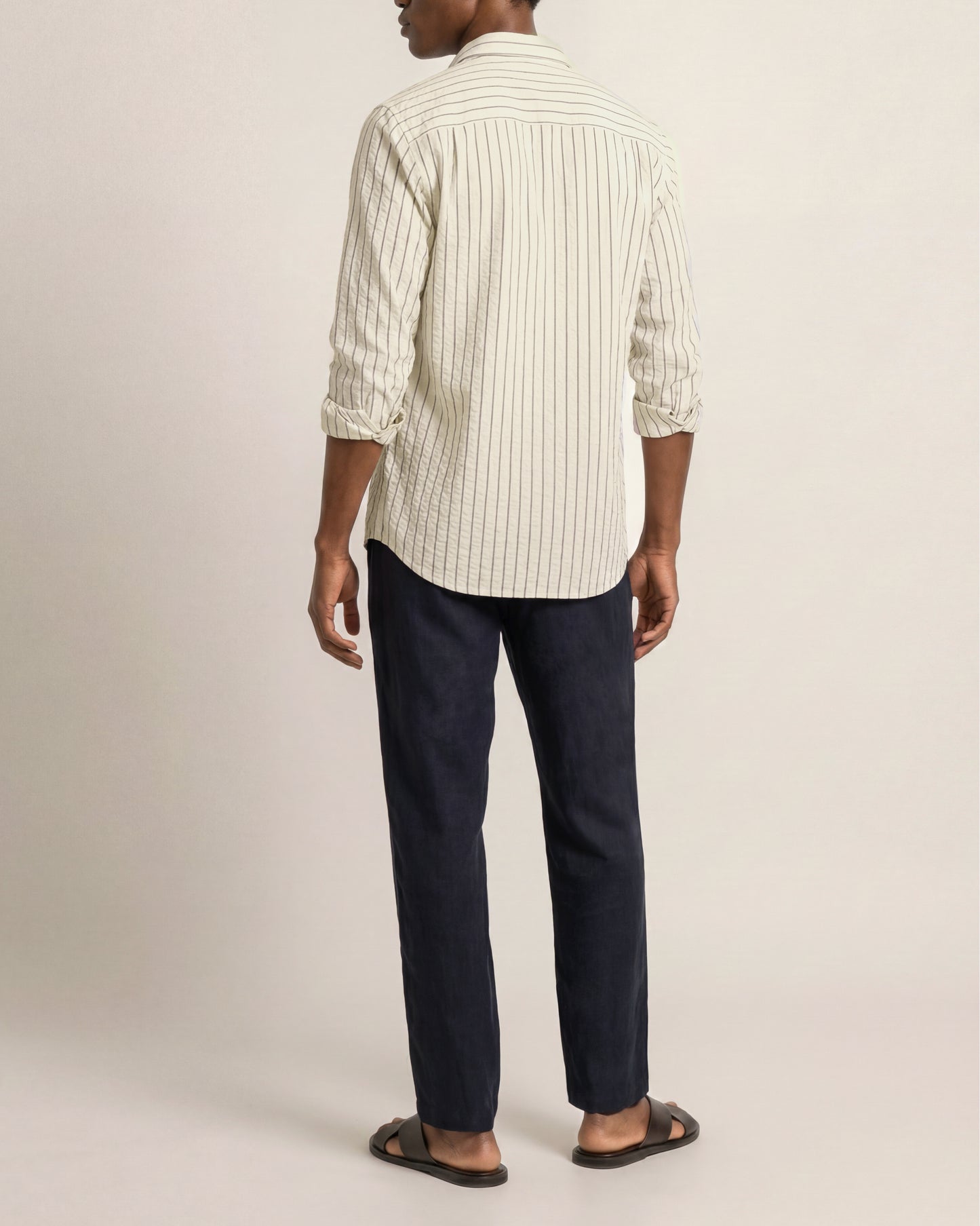 Person wearing a striped shirt and dark pants on a plain background