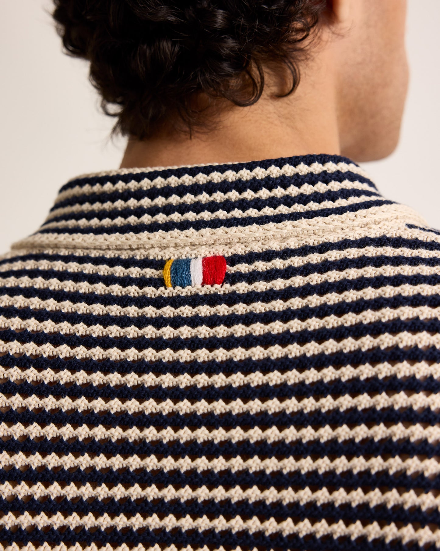 Nautical-style striped shirt with a flag emblem on a plain background