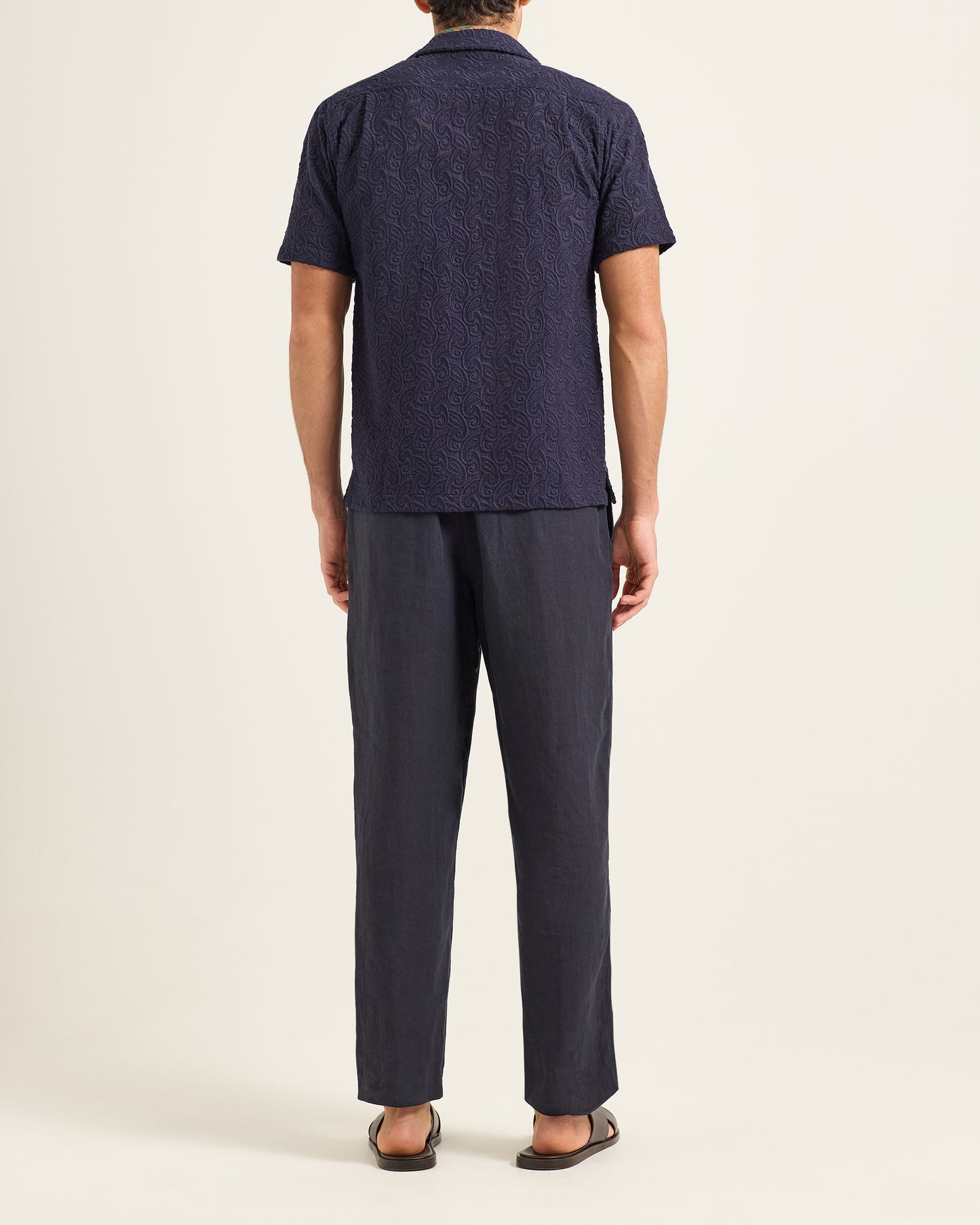 Person wearing a navy blue shirt and pants on a beige background