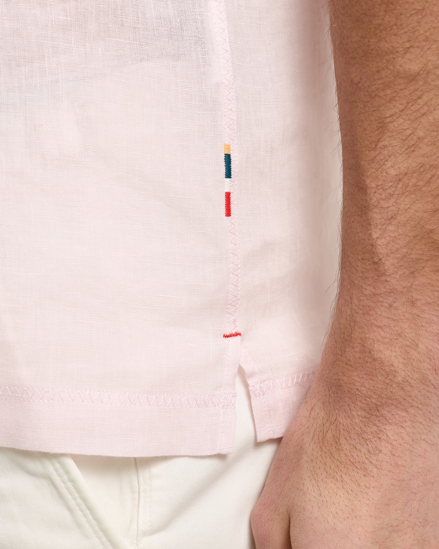 Close-up of a light pink polo with embroidered details on a white background
