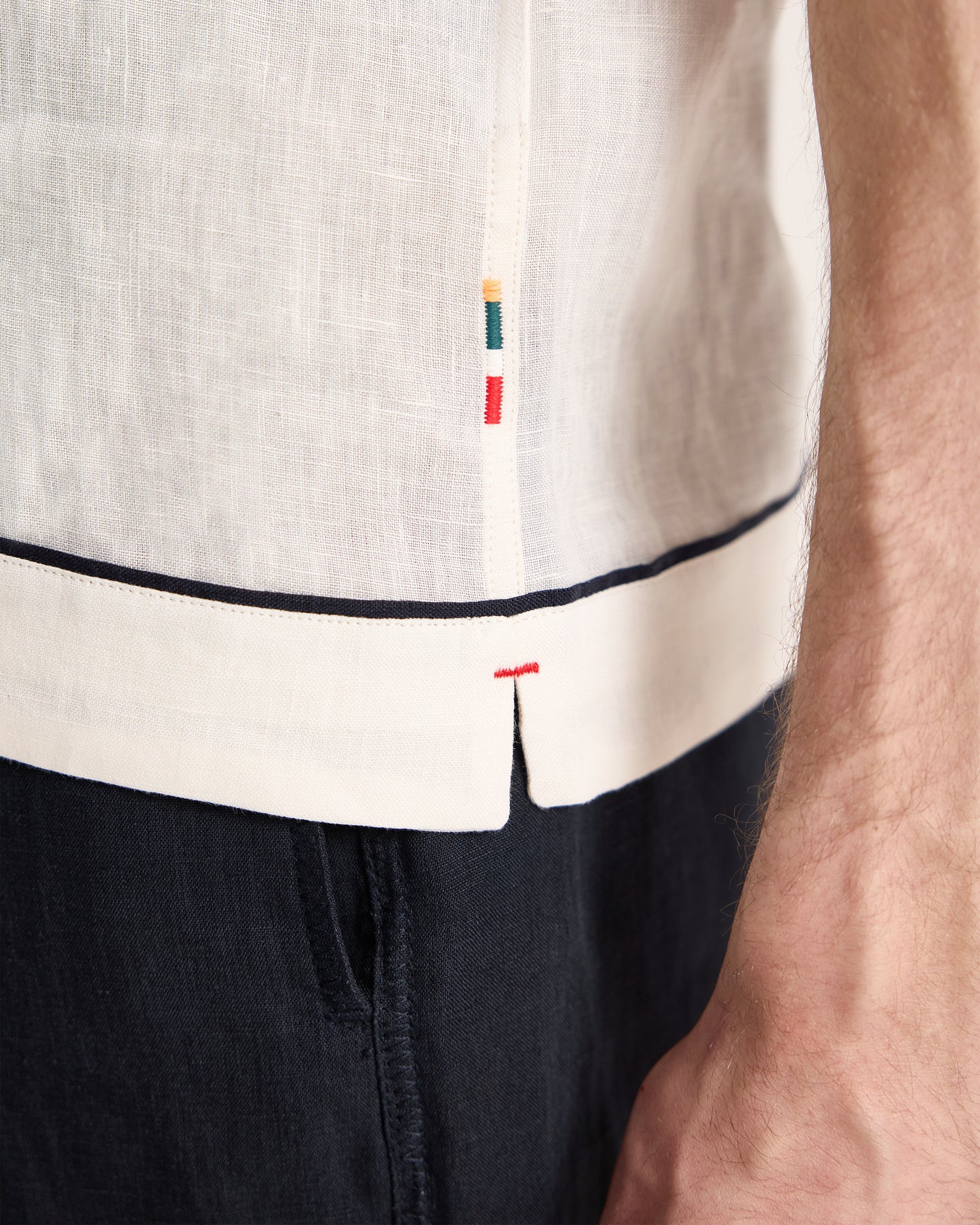 Close-up of a person wearing a white shirt with black trim and colorful buttons.
