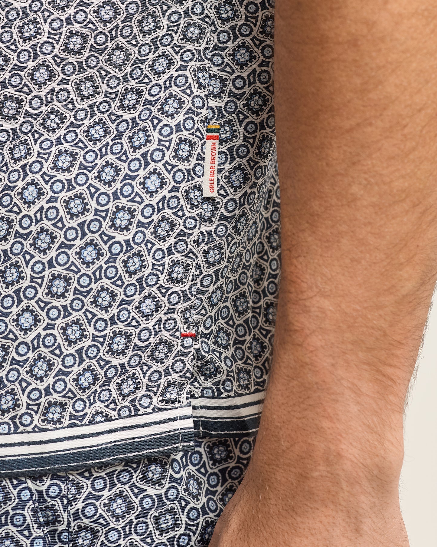 Close-up of a patterned shirt with a brand label on a person wearing it.