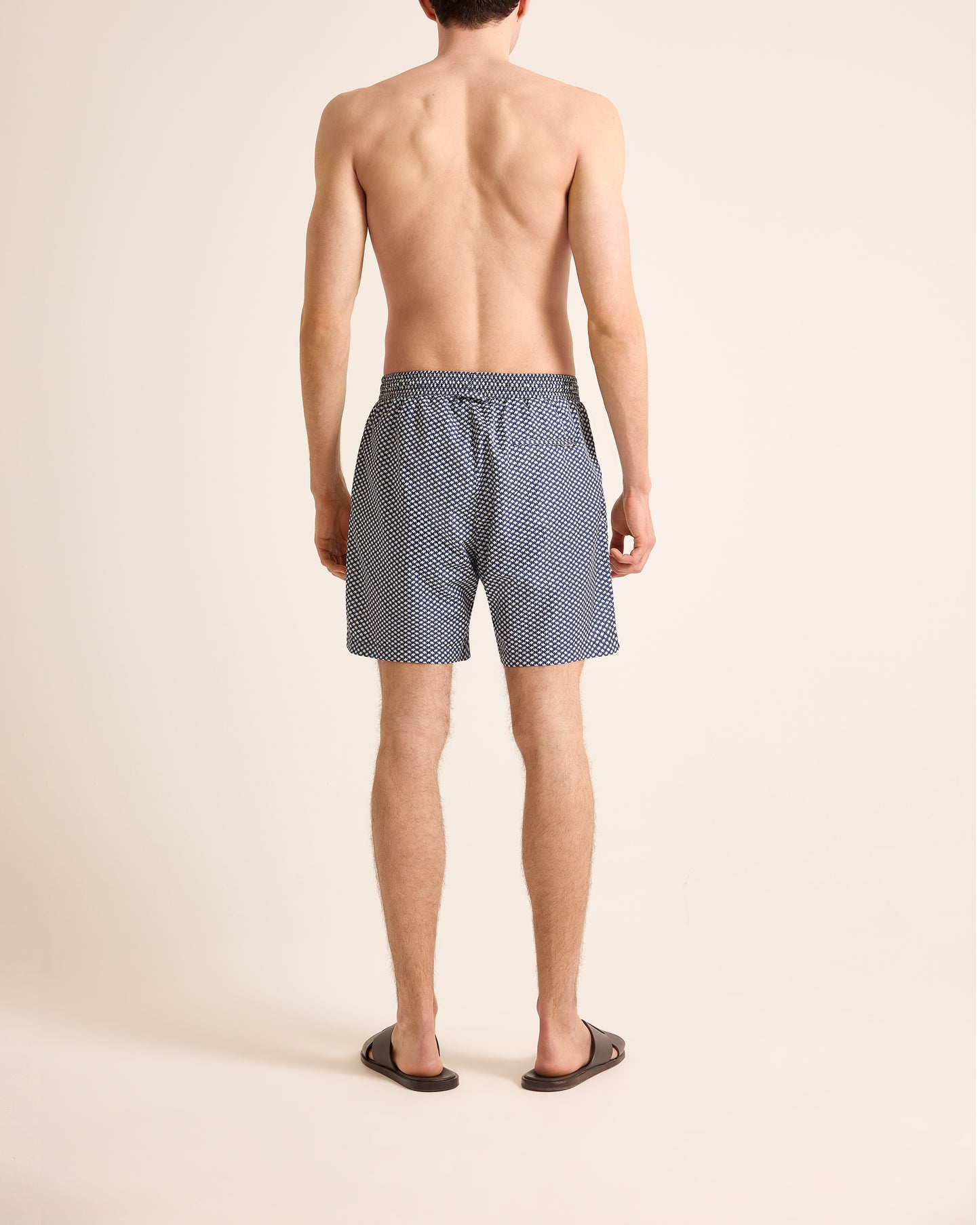 Man wearing blue patterned swim shorts on a beige background