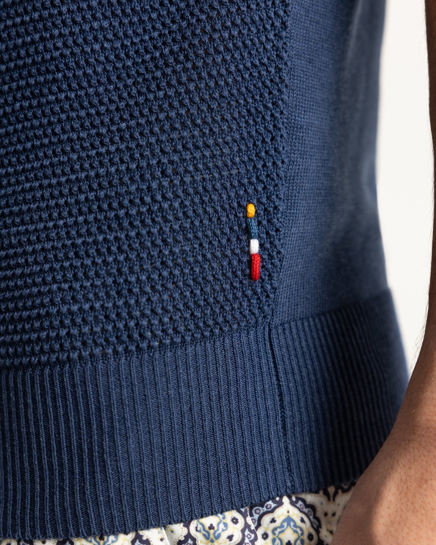Closeup of navy knitted polo shirt with branded embroidery
