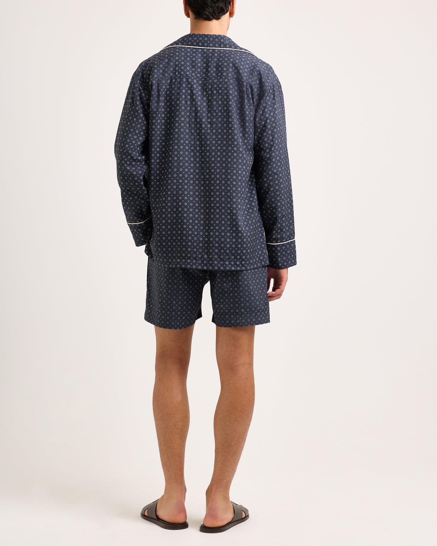 Person wearing a navy blue pajama set with white pattern on a white background