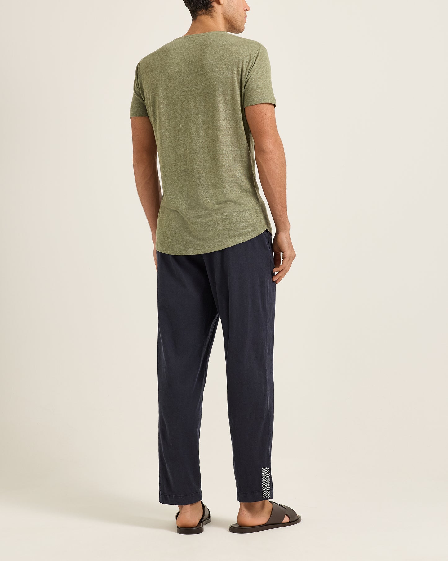 Person wearing a green t-shirt and navy pants on a white background