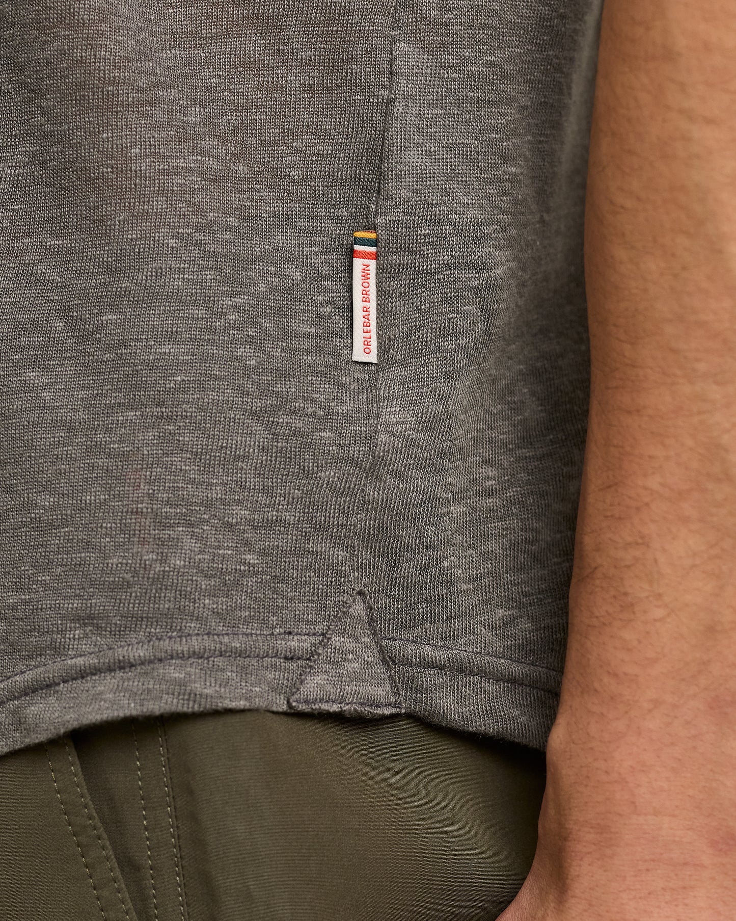 Close-up of a gray shirt with a brand label on a person wearing it.