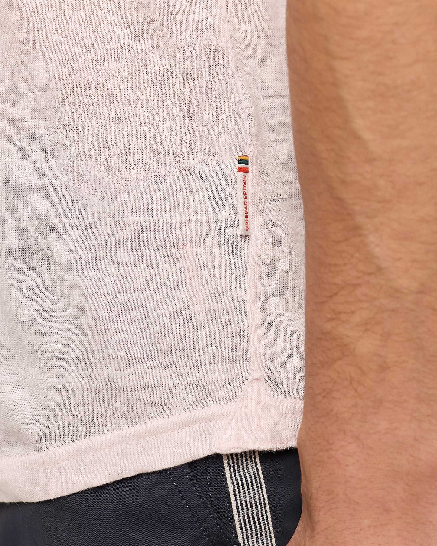 Close-up of a pink garment with a brand logo on a person wearing it.
