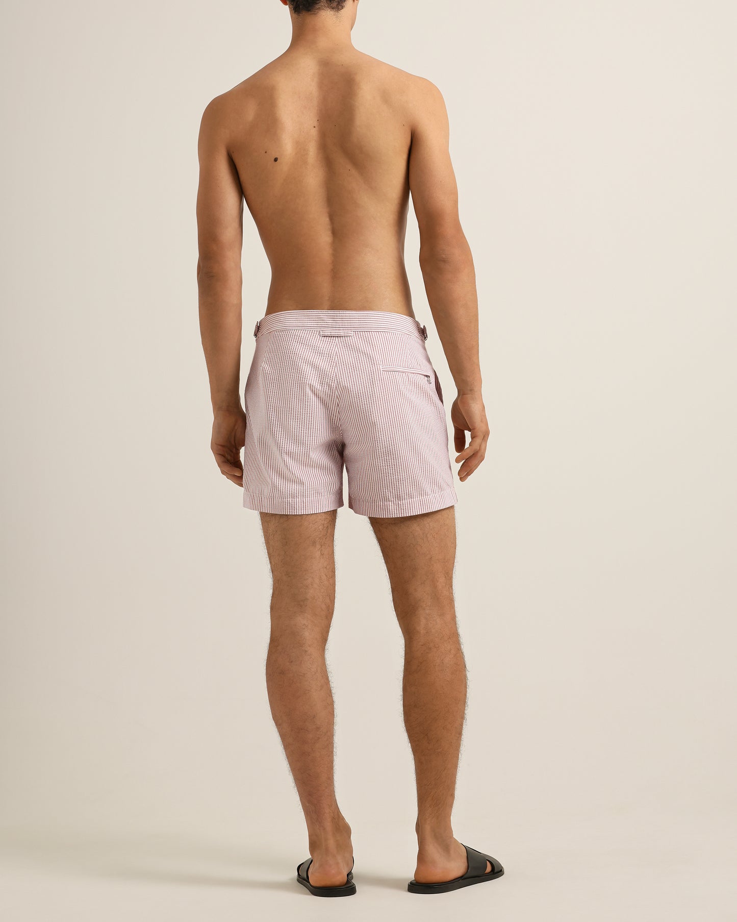 Man wearing light pink shorts on a beige background