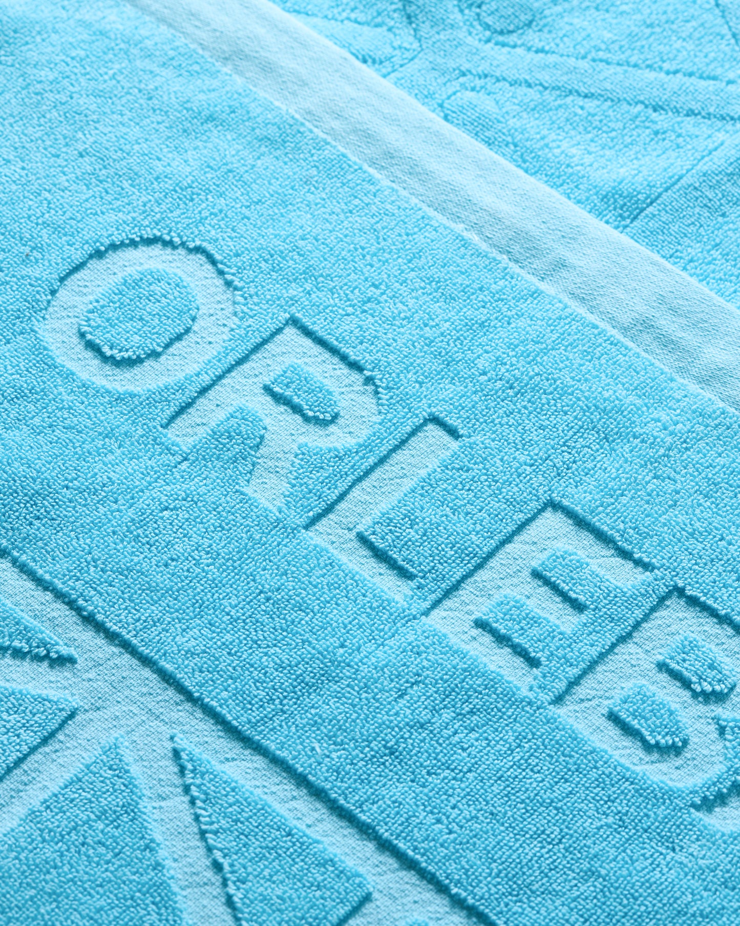 Close-up of a blue towel with 'ORLEB' branding.