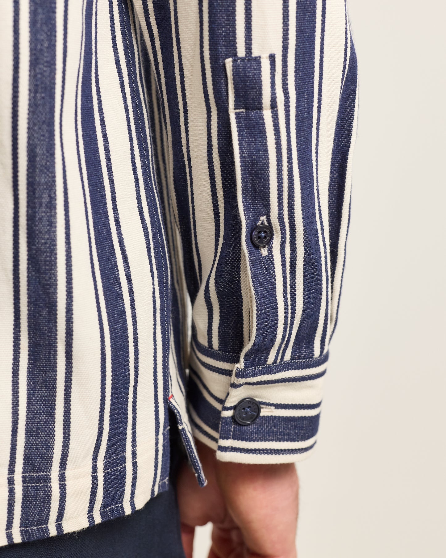 Close-up of a person wearing a blue and white striped shirt with a neutral background