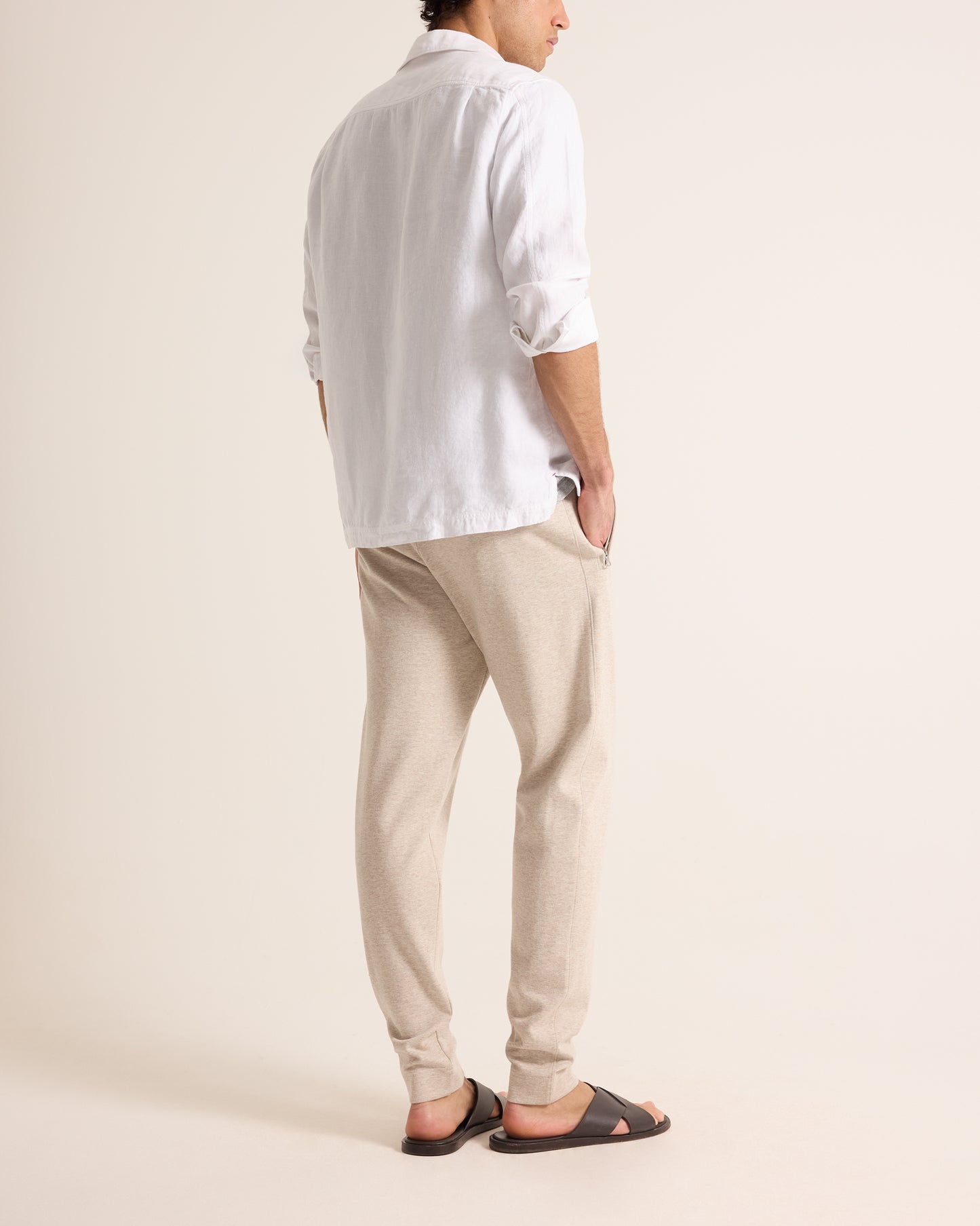 Person wearing a white shirt and beige pants on a plain background