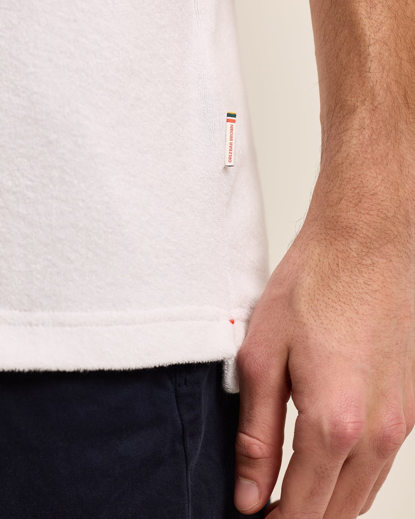 Closeup of white terry towelling polo shirt with Orlebar Brown side logo