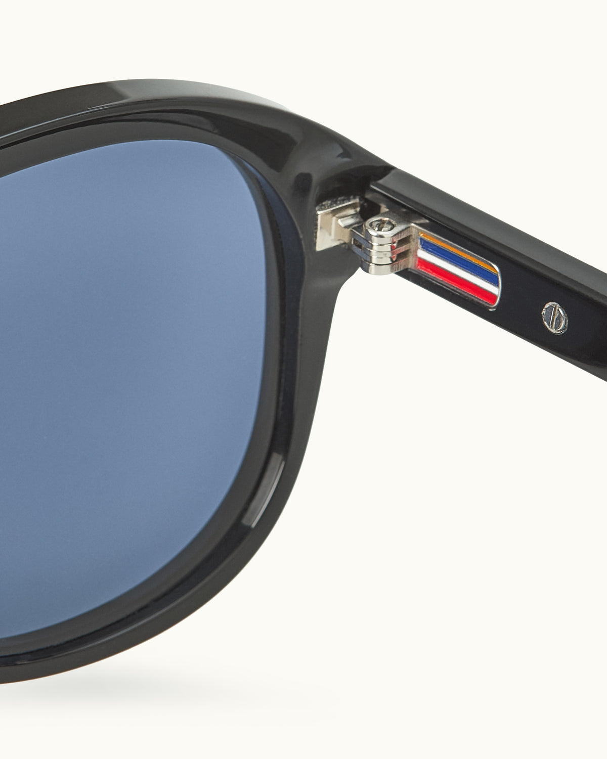Close-up of a black-framed sunglasses with a brand logo on a white background