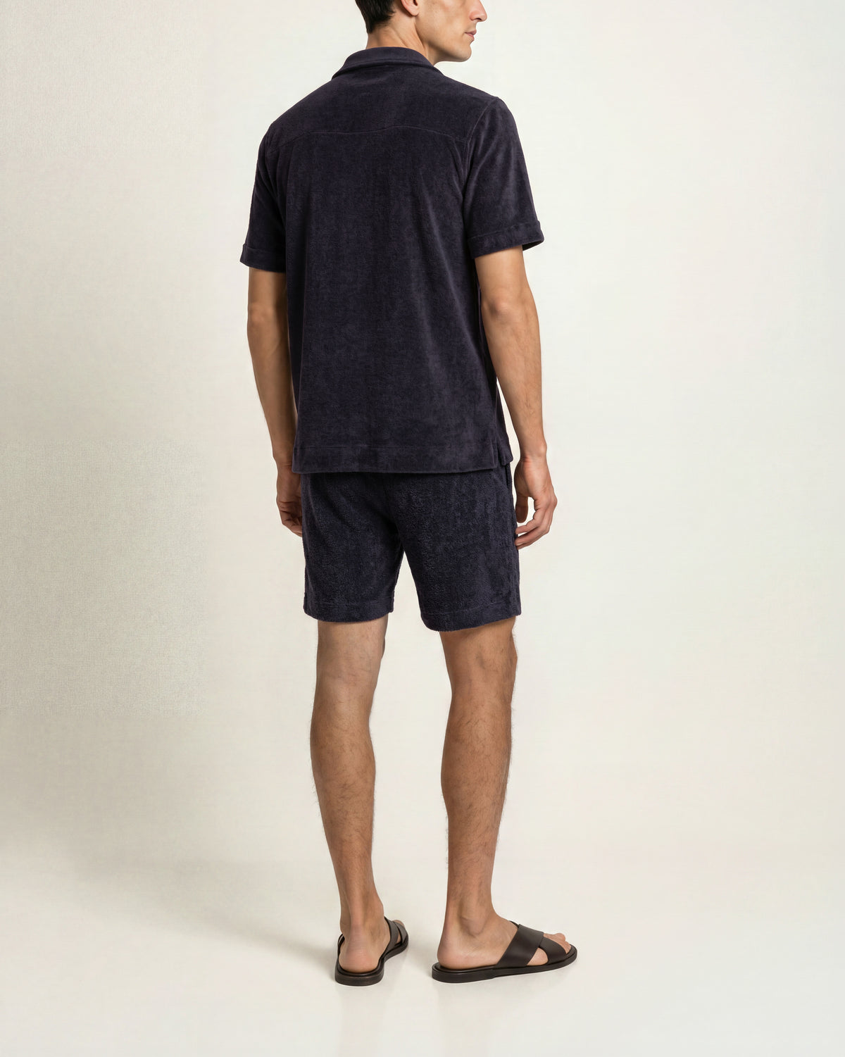 Man wearing navy towelling matching shirt and shorts on a plain background