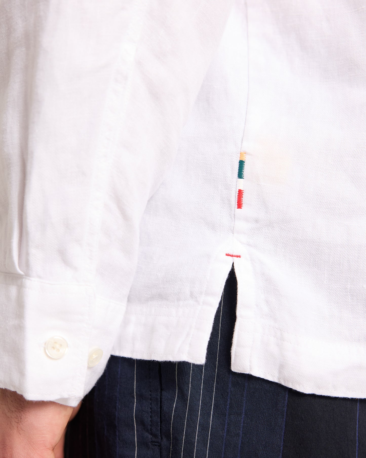 Close-up of a white shirt with colorful buttons and black pants.