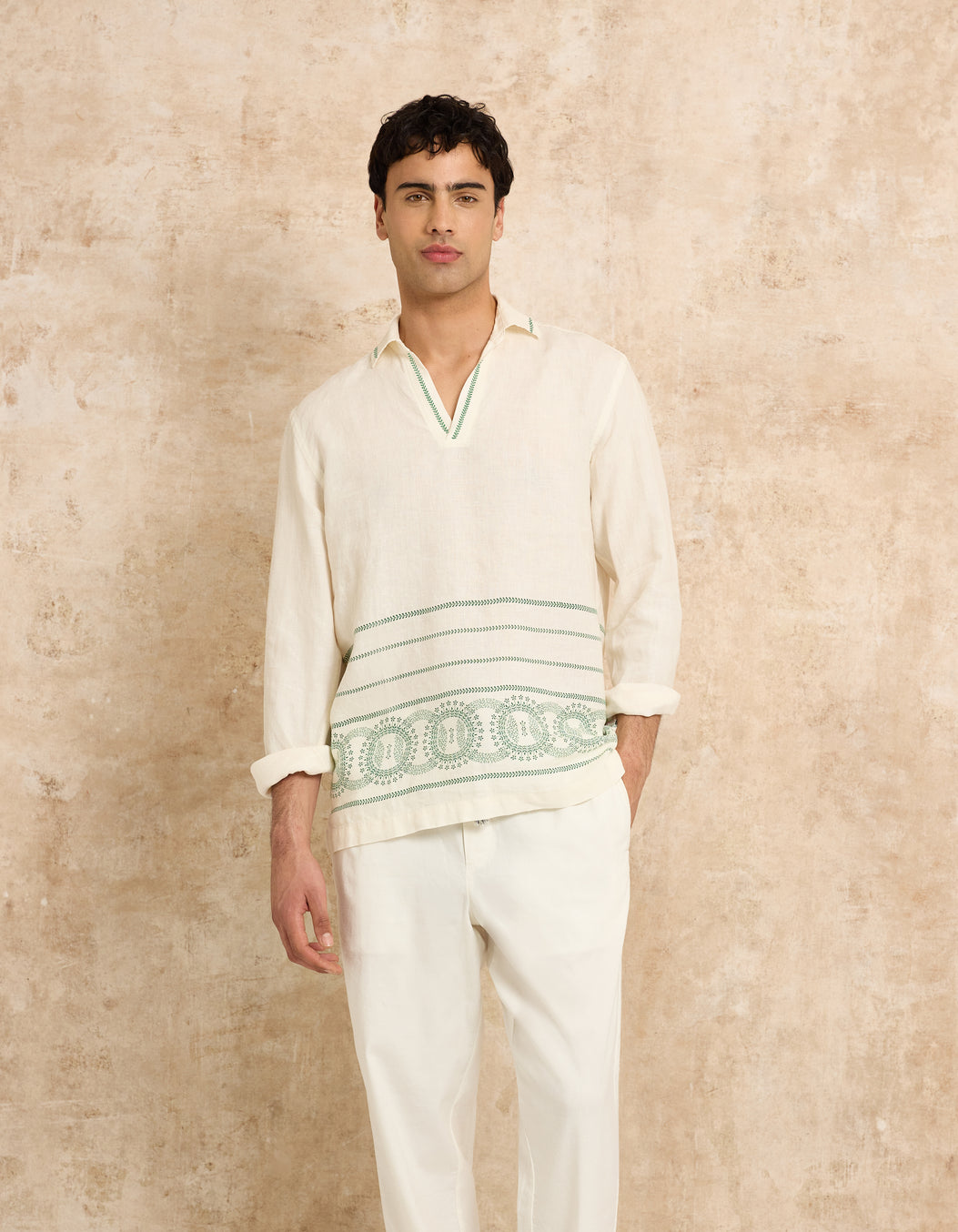 Man wearing a white shirt and trousers on a textured beige background