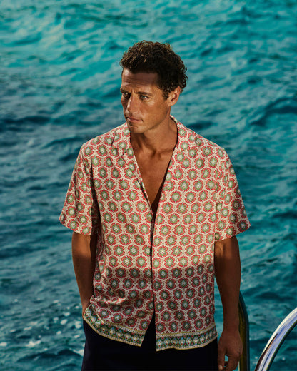Man wearing a patterned shirt standing by the ocean